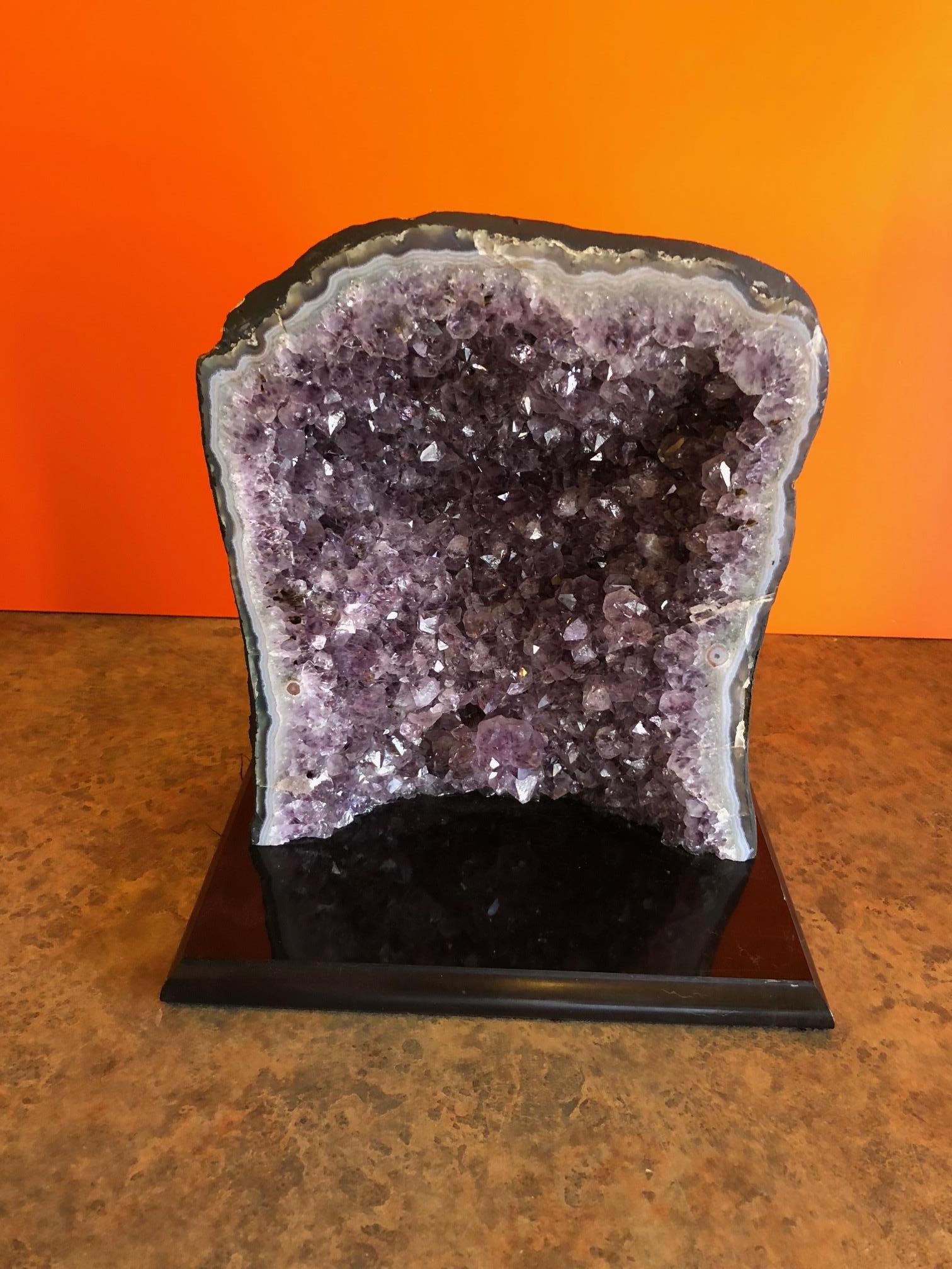 A large solid piece of Brazilian amethyst geode mounted on a beveled black marble base measuring 8