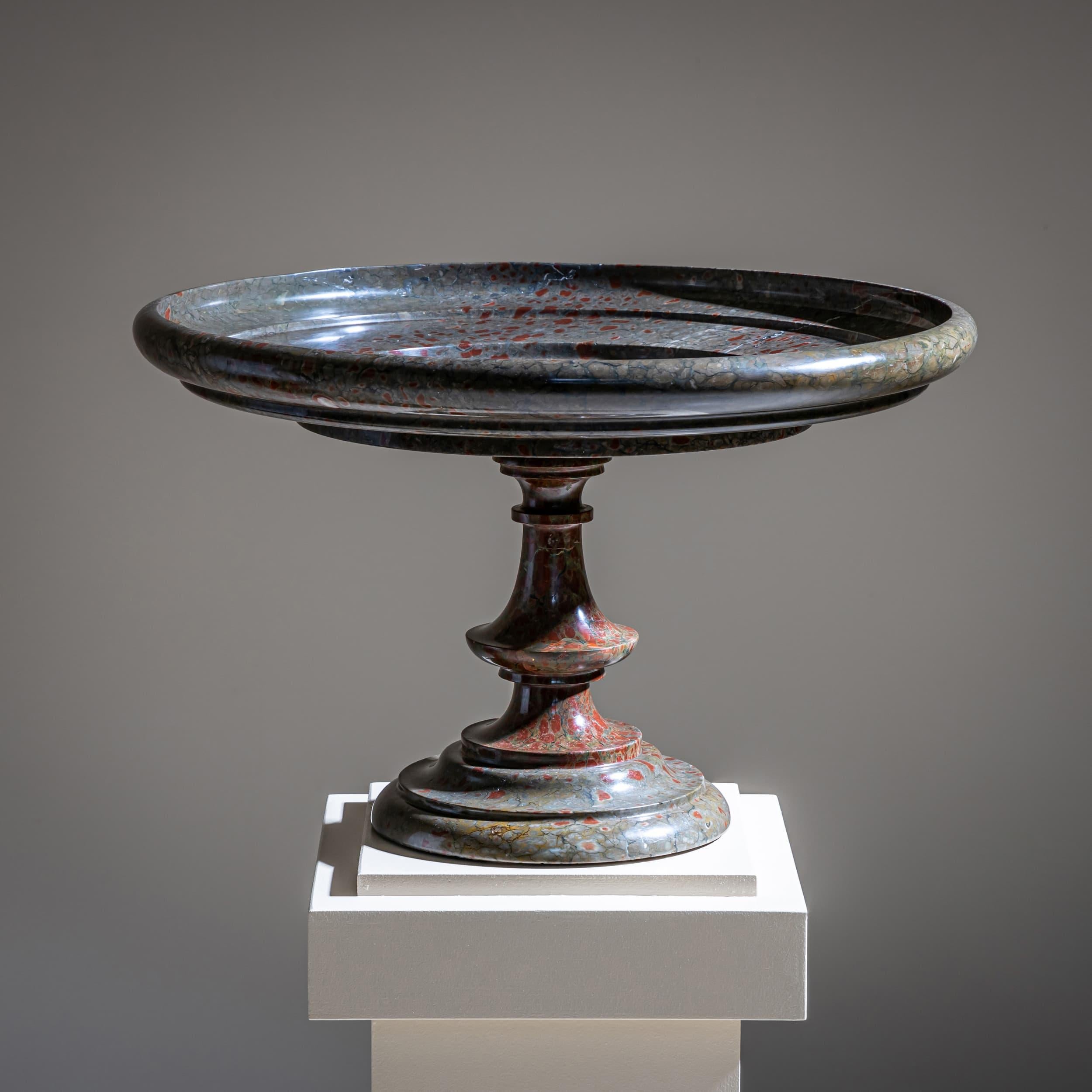 Grande brèche fabriquée à partir de marbre bleu avec des veines rouges frappantes. La forme classique se caractérise par une large coupe peu profonde à bord bas, soutenue par une tige en forme de balustre sur une base circulaire.