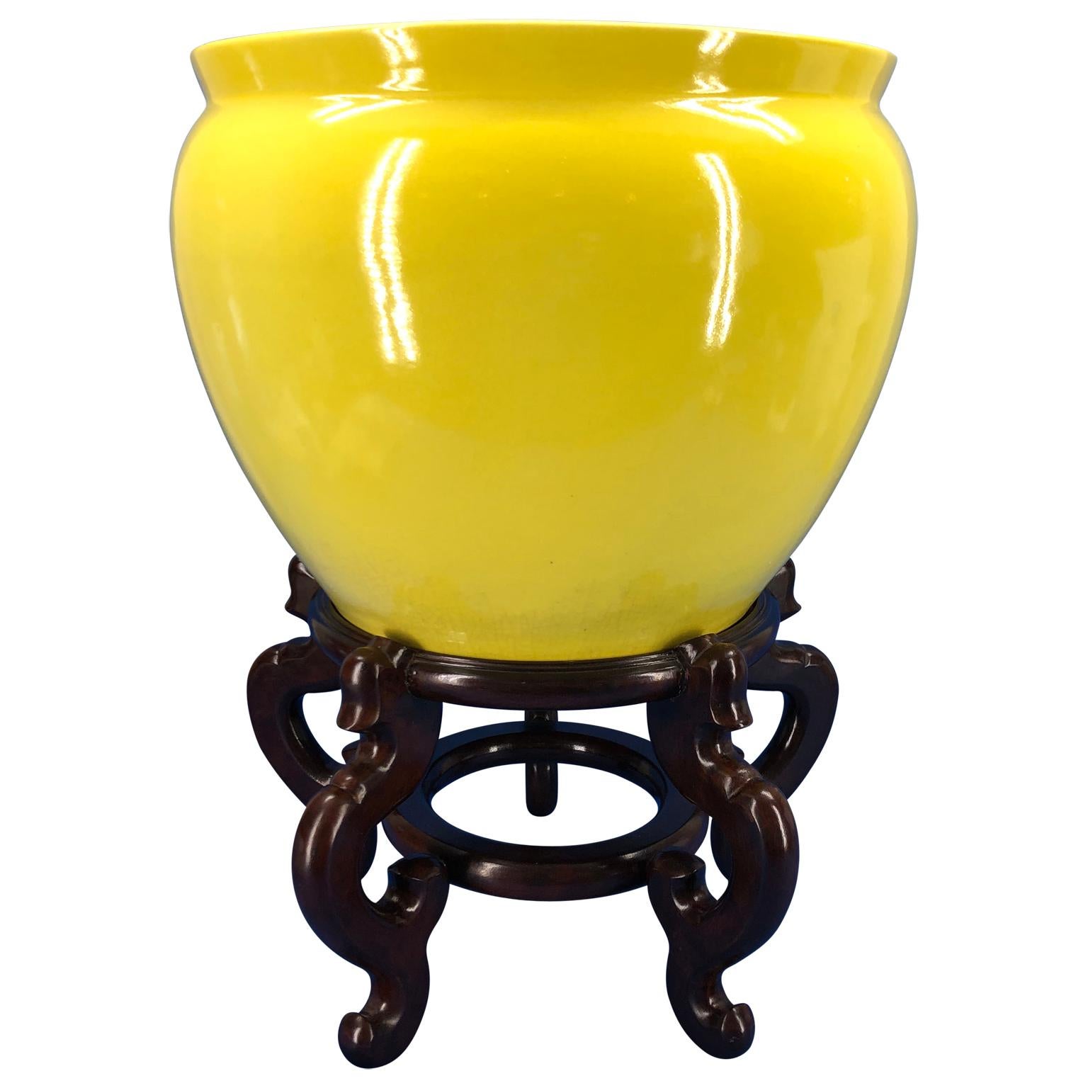 Large yellow hand painted porcelain jardinière bowl on a wooden stand.