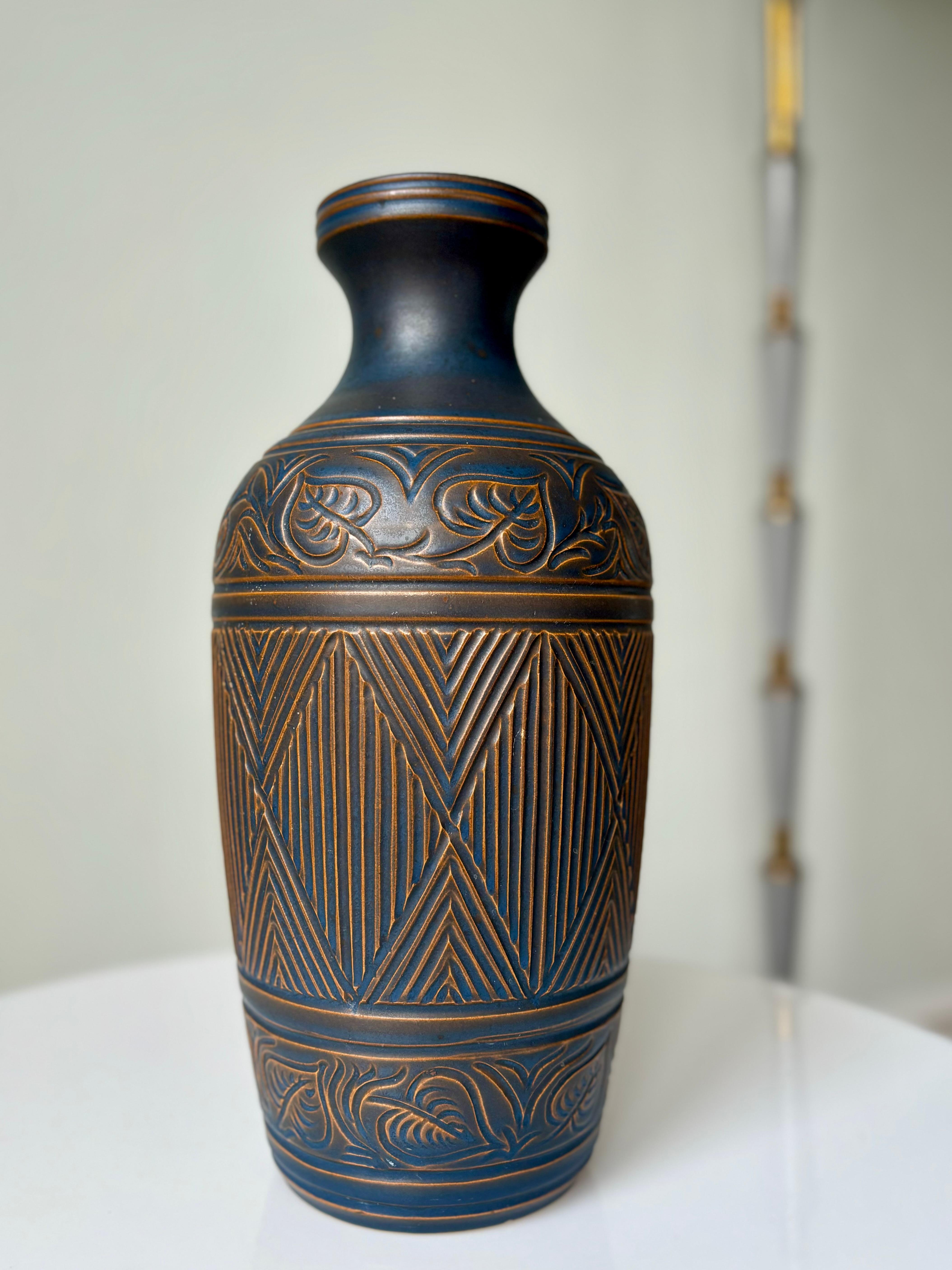 Tall Danish Art Deco style decorated ceramic vase by Bromølle Keramik in 1962. Hand-thrown and hand-carved intricate lined and floral motifs. Caramel brown and dusty dark blue semi-matte glaze. Signed and dated under base. Beautiful vintage