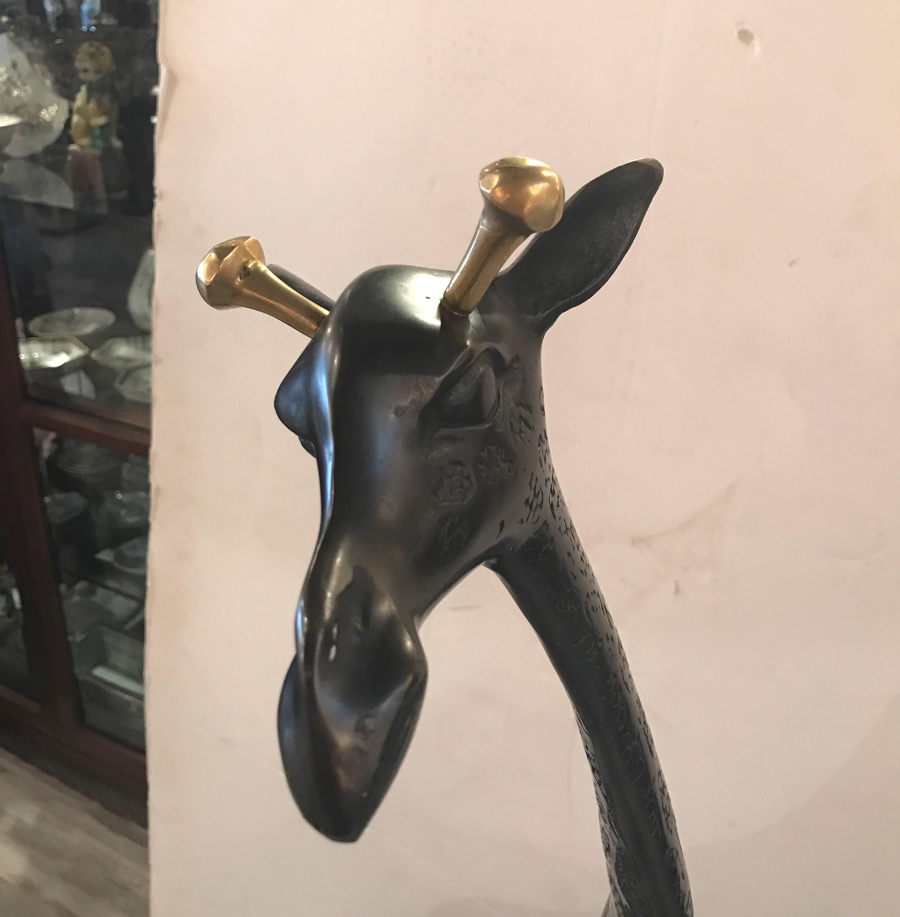 Whimsical patinated sculpture of a giraffe with brass horns. The body with a giraffe pattern all over. Tall sleeks and slender