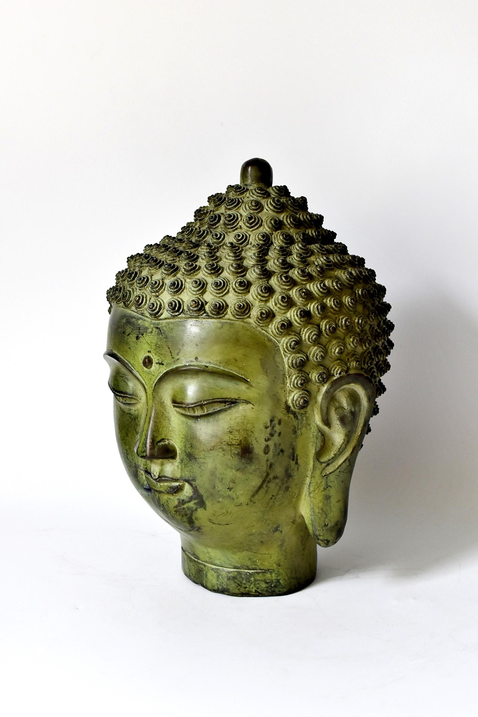 A beautiful large Buddha head. The style of the piece is of the Tang dynasty era, with a full face, long ear lobes and scrolled hair style. Beautiful, finely defined facial features convey a sense of calm and serenity.
