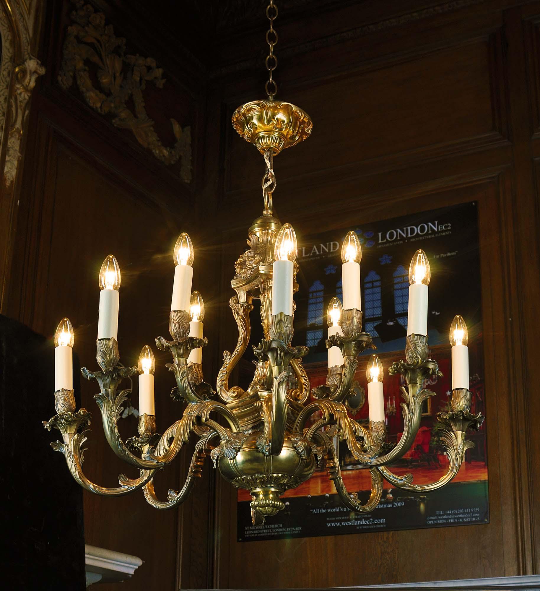 A large ornate bronze chandelier in the Rococo manner with a highly ornate bulbous stem terminating in a large flattened orb and from which the twelve scrolling, acanthus clad branches emanate. A delightful pineapple in a cup is a central feature