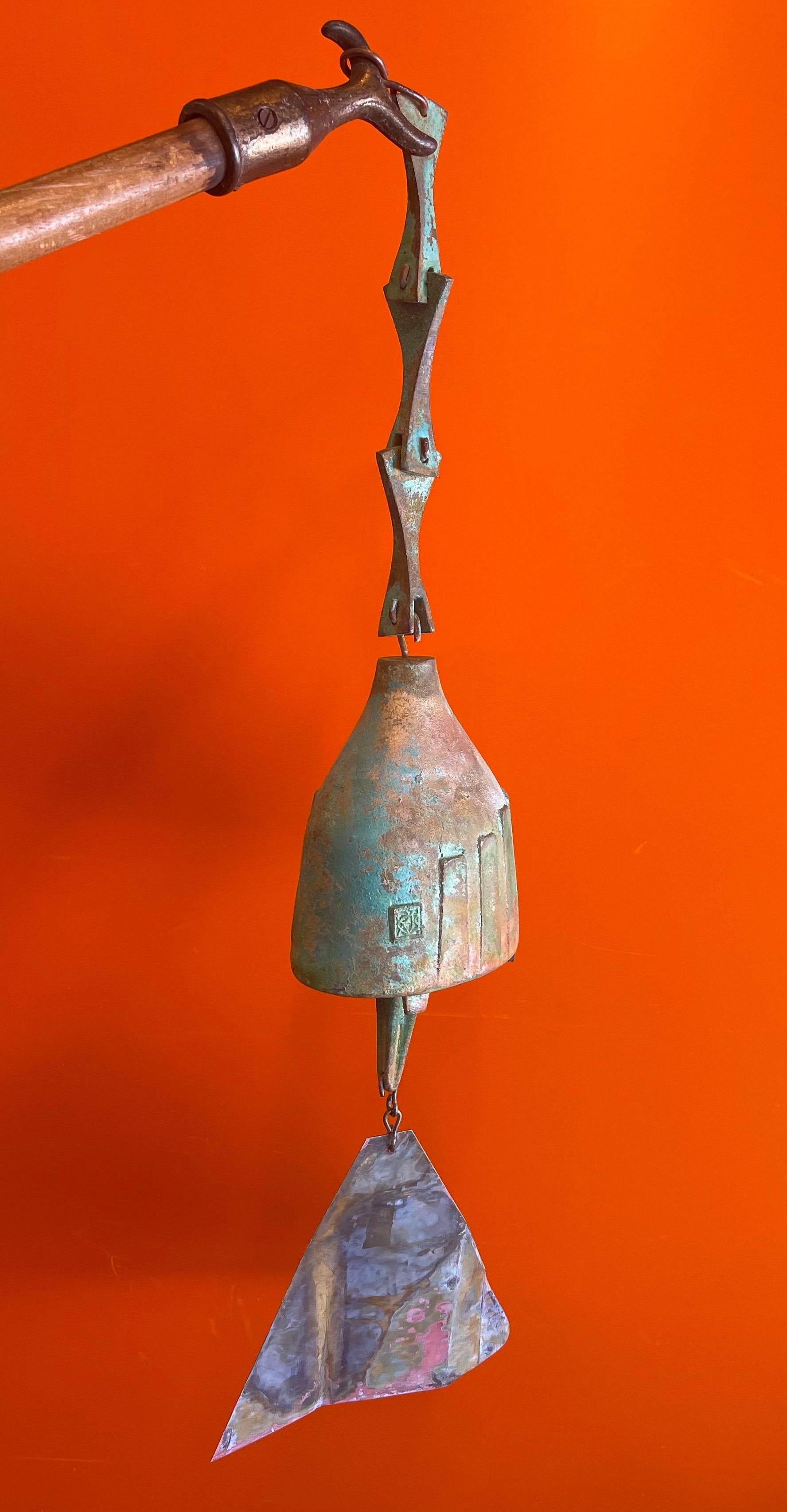 Large bronze Cosanti wind bell with hanging bracket by Paolo Soleri, circa 1980s. The bell has a beautiful patina with rich teal, green, brown, red and gray colors. The total length of the piece is 24.5