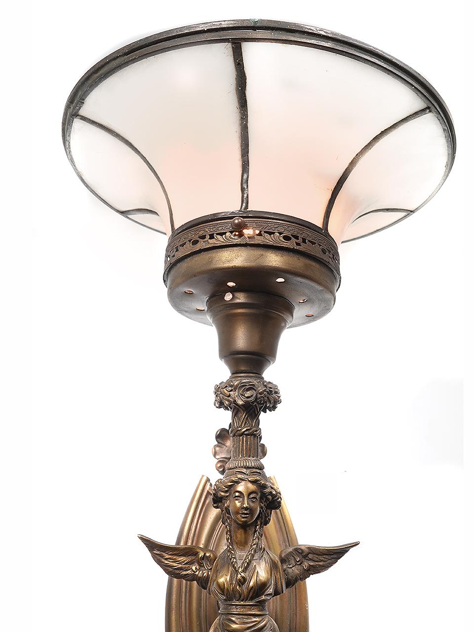 This is an impressive torch sconce that is 3 foot tall. This example has a flared leaded glass shade that gives it a unique and rich look. The bronze casting is nicely detailed with a winged angel and floral details.The shade has a 12 inch diameter.