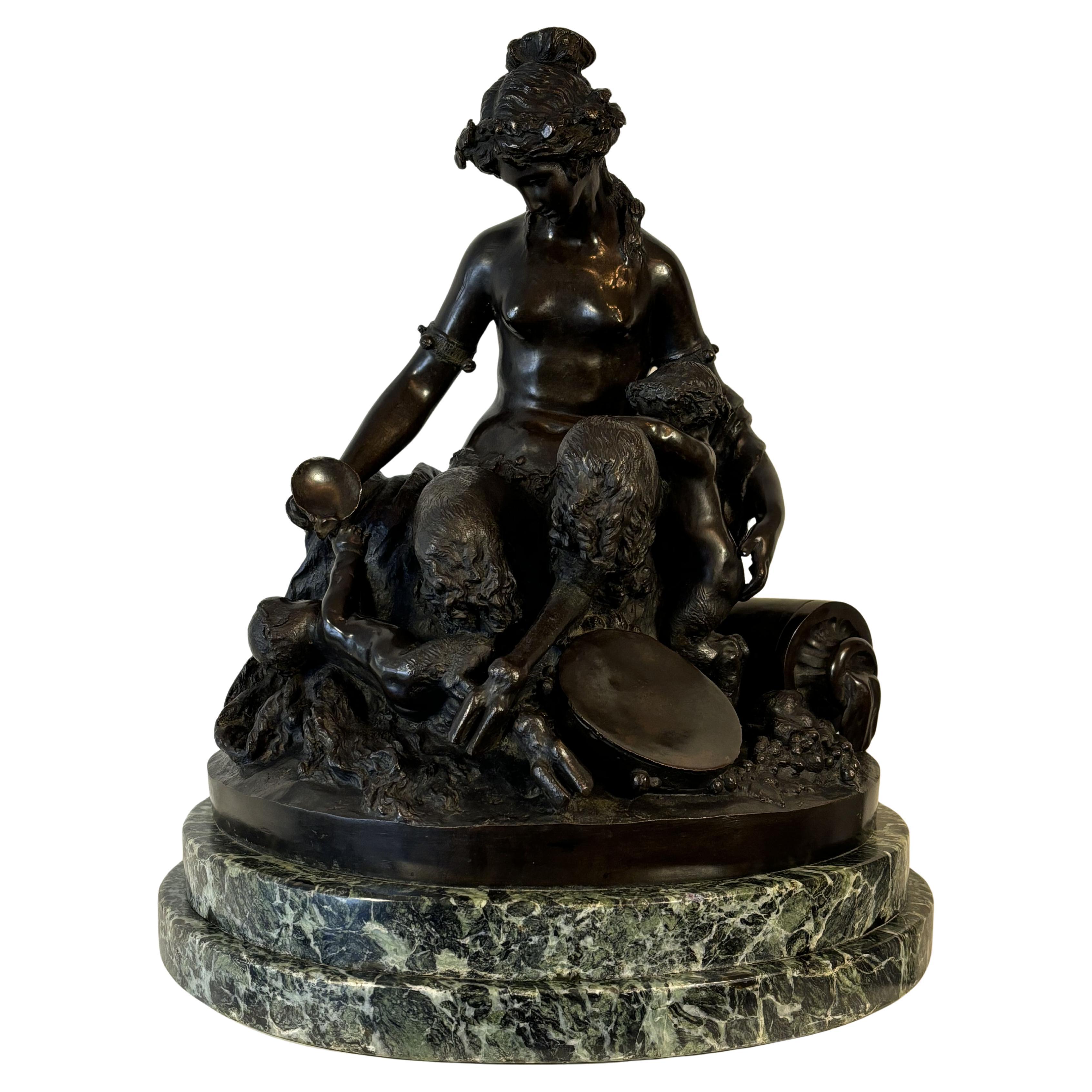 Grand groupe en bronze à patine brune signé Clodion sur la base du groupe, datant du XIXe siècle, représentant un faune avec ses deux enfants, l'un à genoux, l'autre couché, sur le thème du bacchus. 
La mère tend une coupe de vin à l'enfant, le vin
