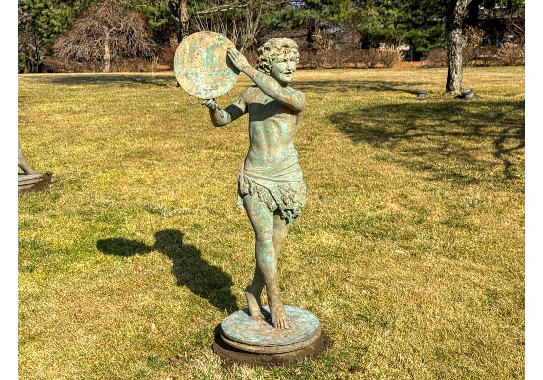 Impressionnante statue de jardin en bronze représentant un jeune néoclassique portant une écharpe en molleton autour de la hanche et marchant sur une base circulaire avec un tambourin surélevé. Le bronze est monté sur une plate-forme métallique