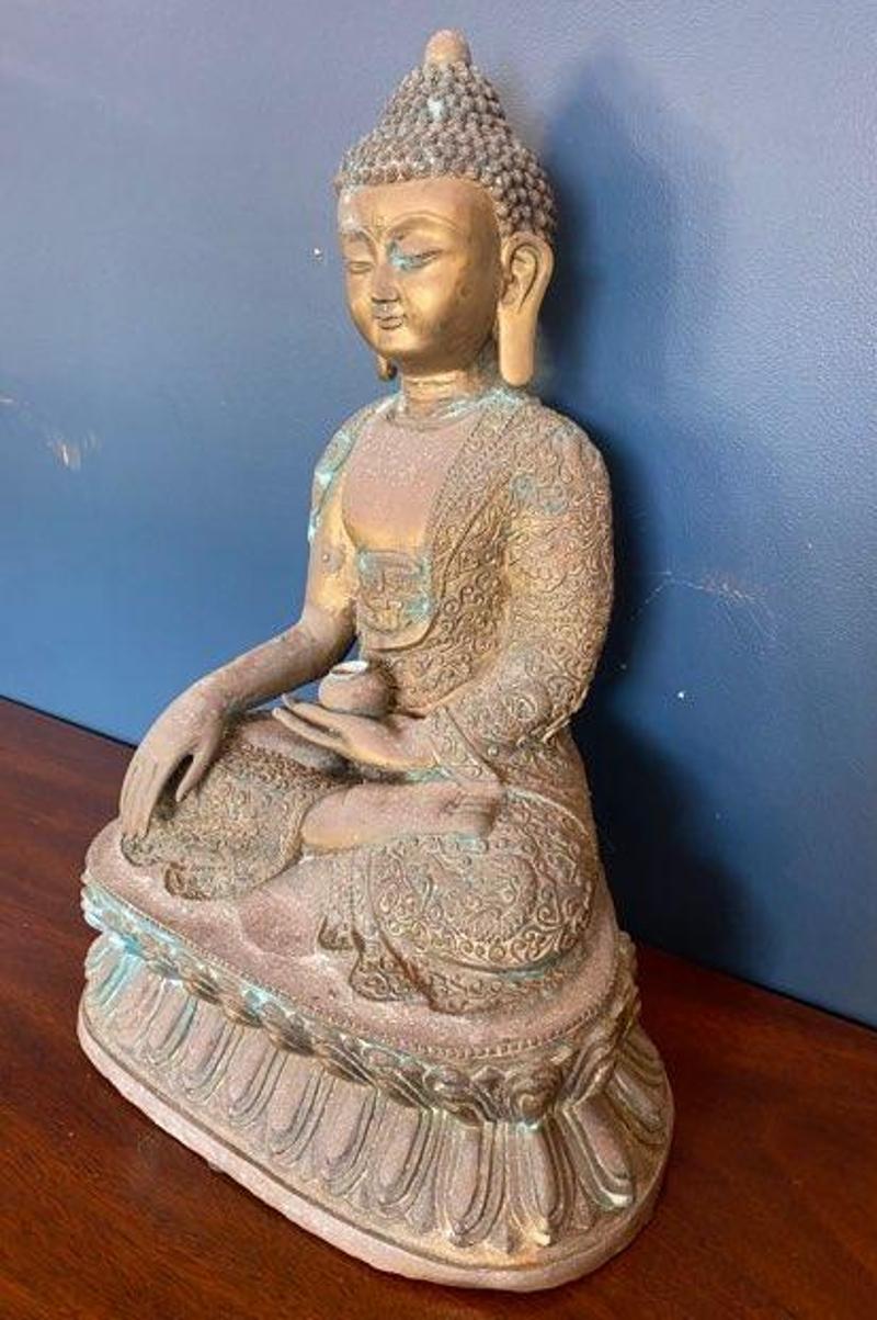 Large bronze sculpture of Thai Buddha in seated position wearing a patterned dhoti, with a small spherical ball in his hands. Thailand, 1900s. 
Measures: 25