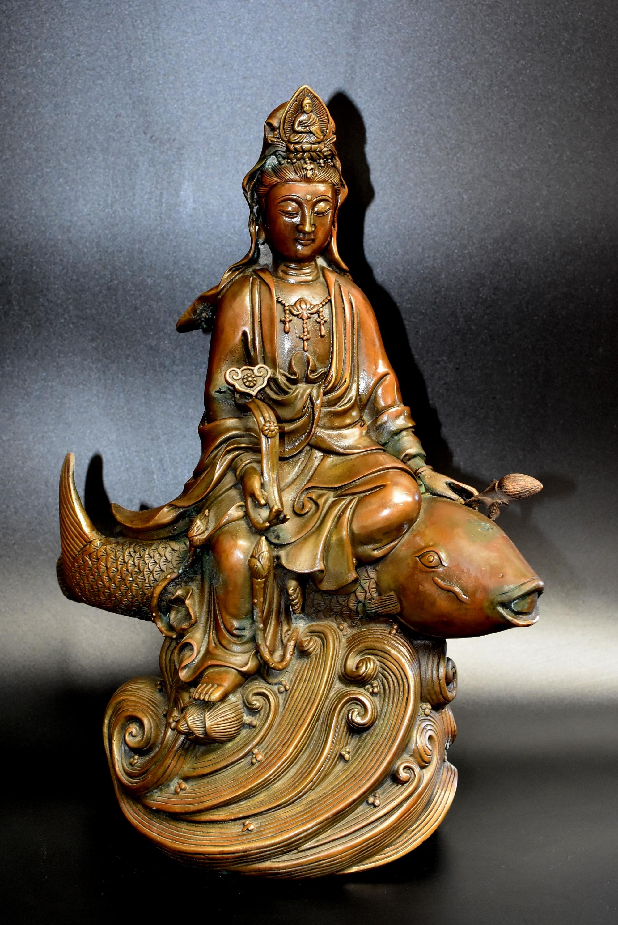 A substantial, 14 lb statue of Kwan Yin, the Goddess of Mercy. Holding a lotus in one hand and a ruyi scepter in the other, she is seated on a large koi fish above water waves. Kwan Yin is believed to bring blessings and grant wishes. In this
