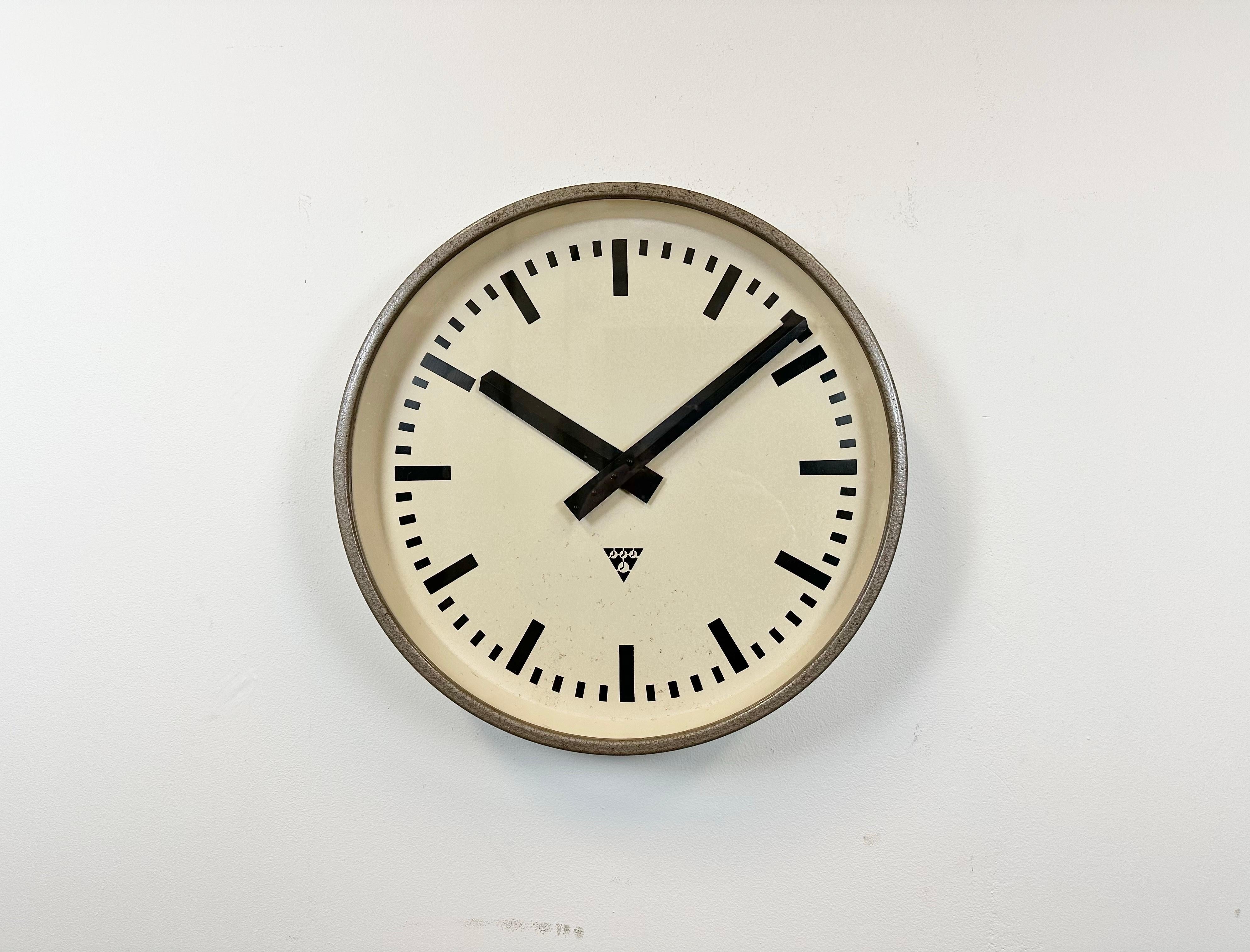 Pragotron wall clock made in former Czechoslovakia during the 1960s. It features a brown hammerpaint metal frame, a metal dial and a clear glass cover. The piece has been converted into a battery-powered clockwork and requires only one AA-battery.