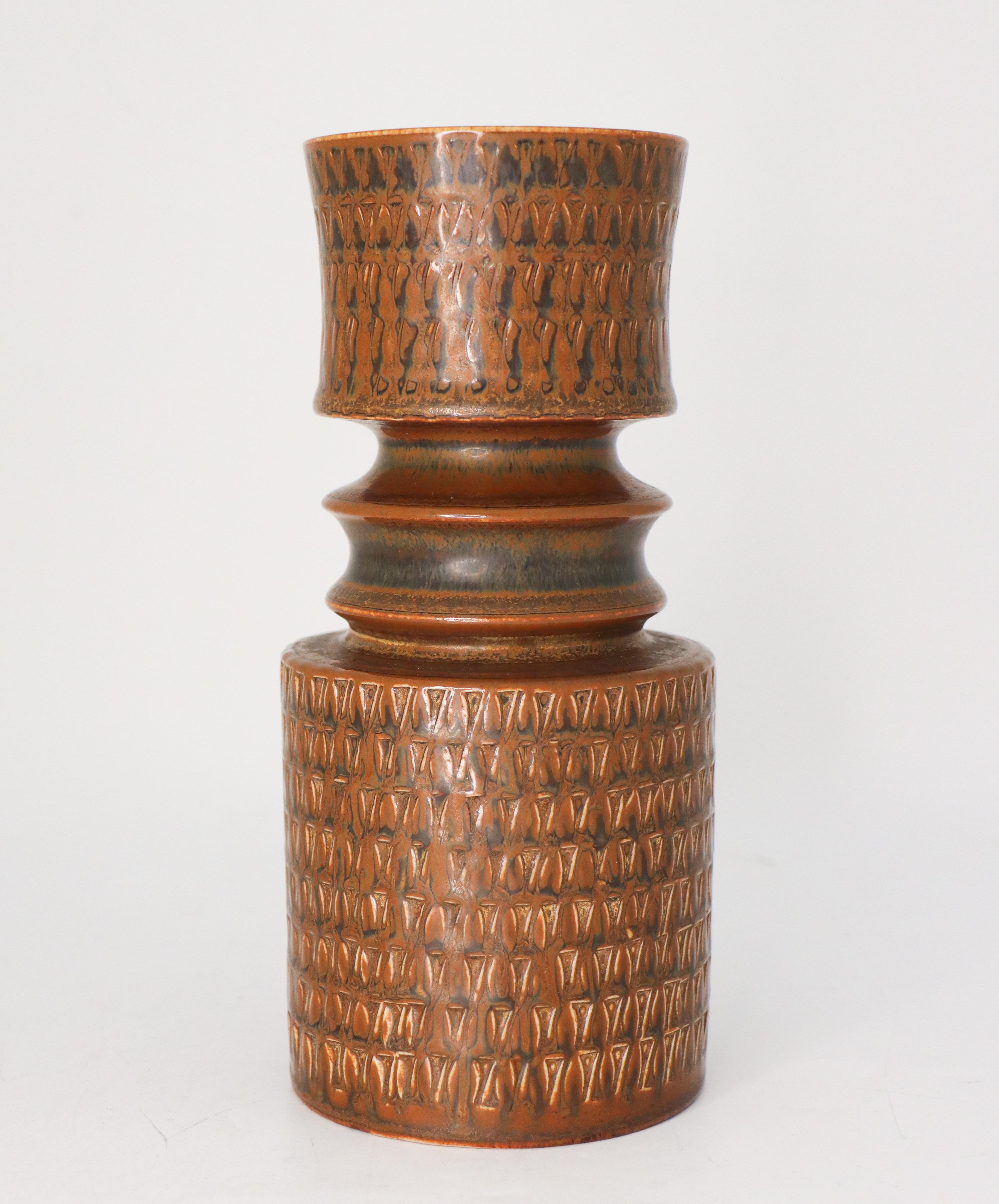 A large brown stoneware vase with a relief decor designed by Stig Lindberg at Gustavsberg. It is 21 cm high and in very good condition. This vase was designed in 1962.
