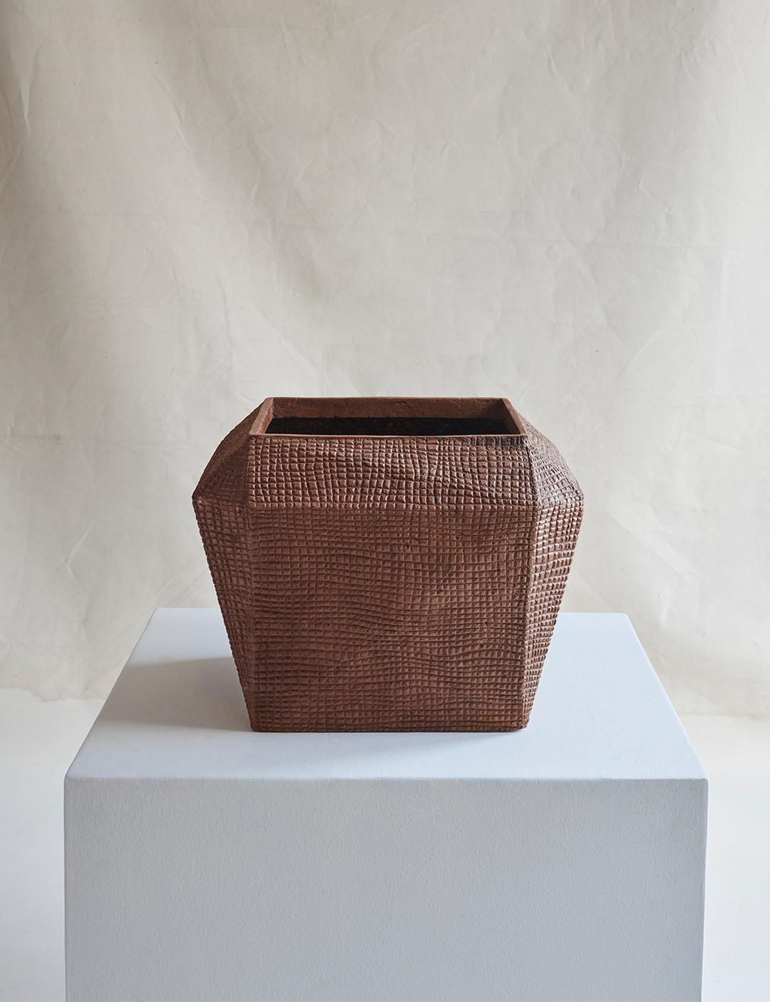 A large, broad geometric square vessel featuring a wide mouth, imprinted with a small repeating tactile texture.

For indoor or outdoor use, in covered environments.

Dimensions (in): 16