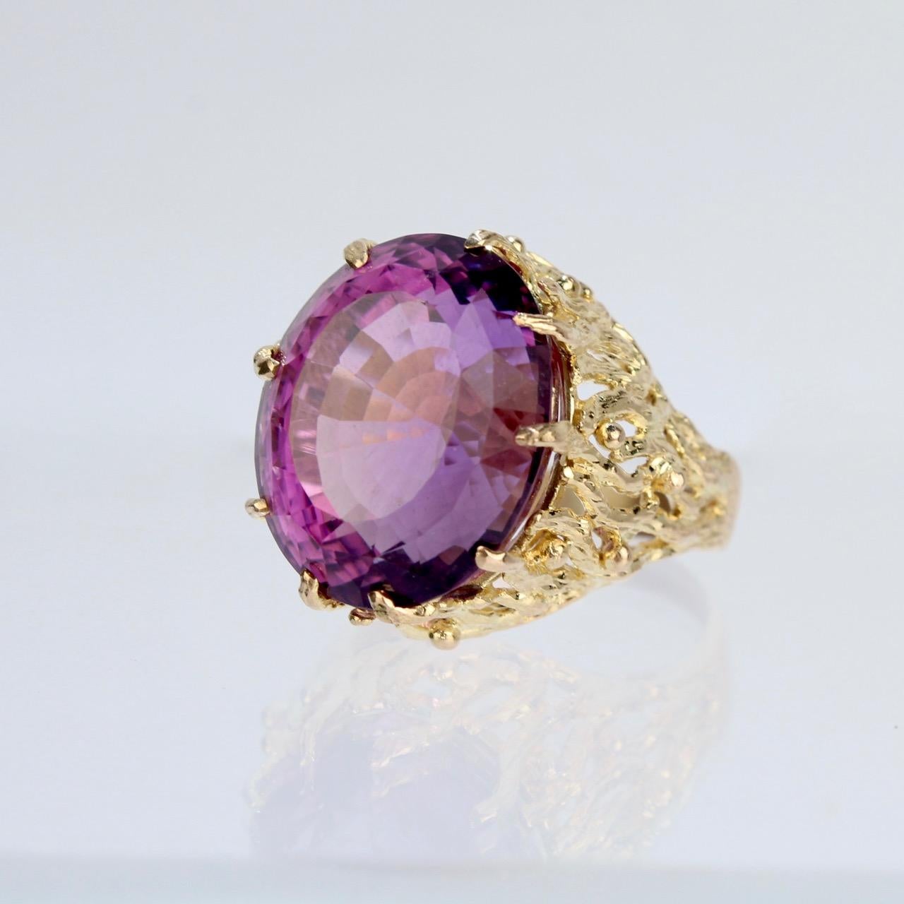 A large Brutalist gold and amethyst ring.

With a substantial oval-cut amethyst gemstone (20+ carat) prong set in a sinuous, intertwined structural 14k gold Brutalist setting. The gold setting has ample openwork that offsets the weight and size of
