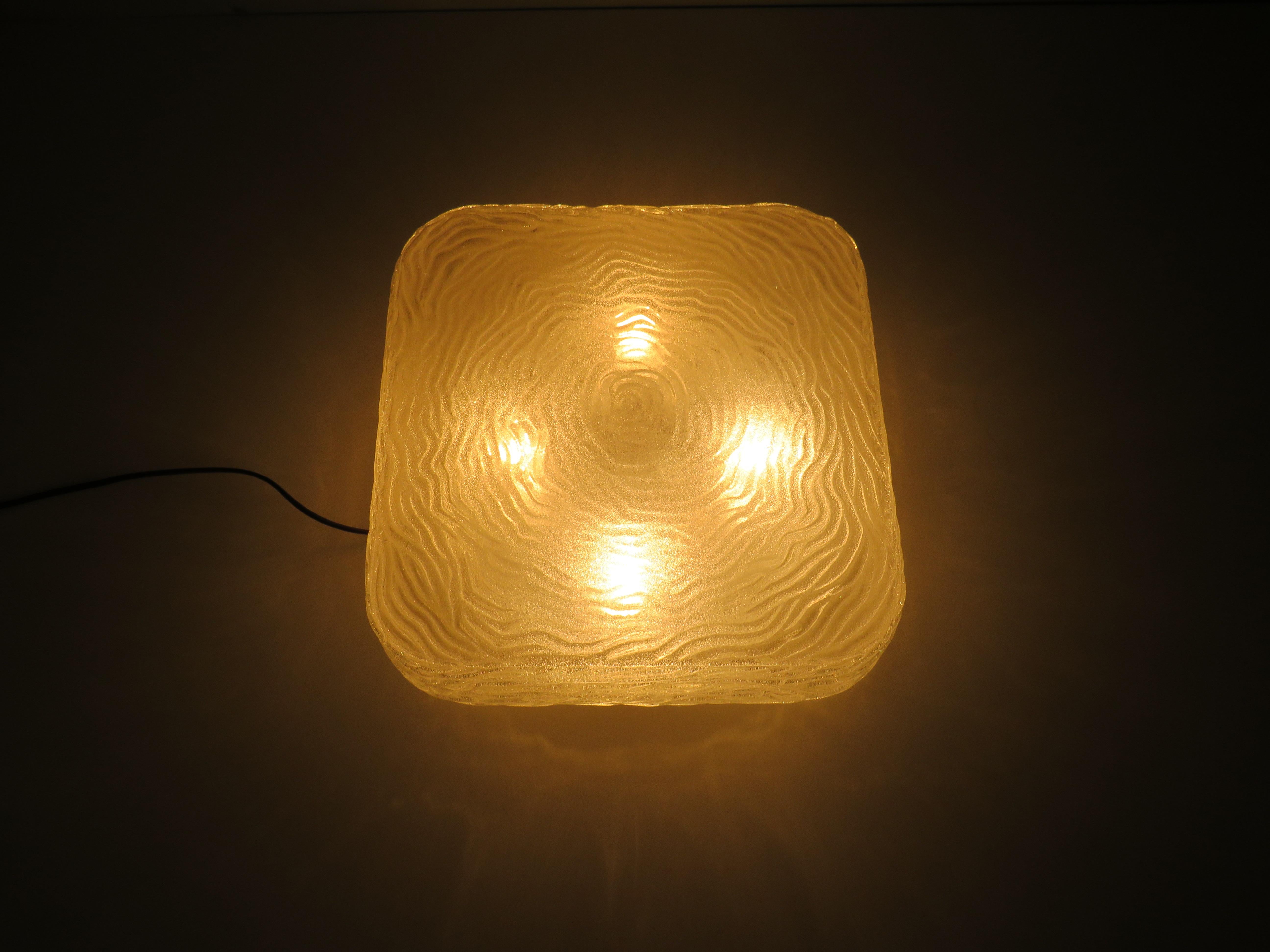 Extra large flush mount or wall lamp made of thick glass with a fingerprint motif and an ice glass effect.
The ceiling lamp has a square shape with rounded corners and is 37 by 37 cm wide. The height of the ceiling lamp is 13 cm. The article has a