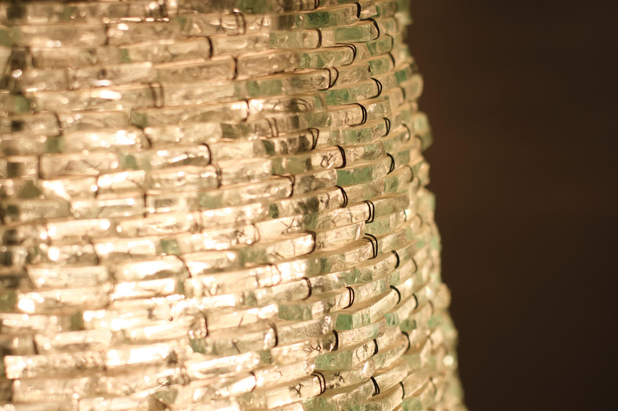 Grand lampadaire en forme de cône en verre. De petites pièces allongées en verre transparent cousues individuellement les unes aux autres par un fil fin. Deux grandes ampoules E27 . Pièce unique faite à la main. Bon état .