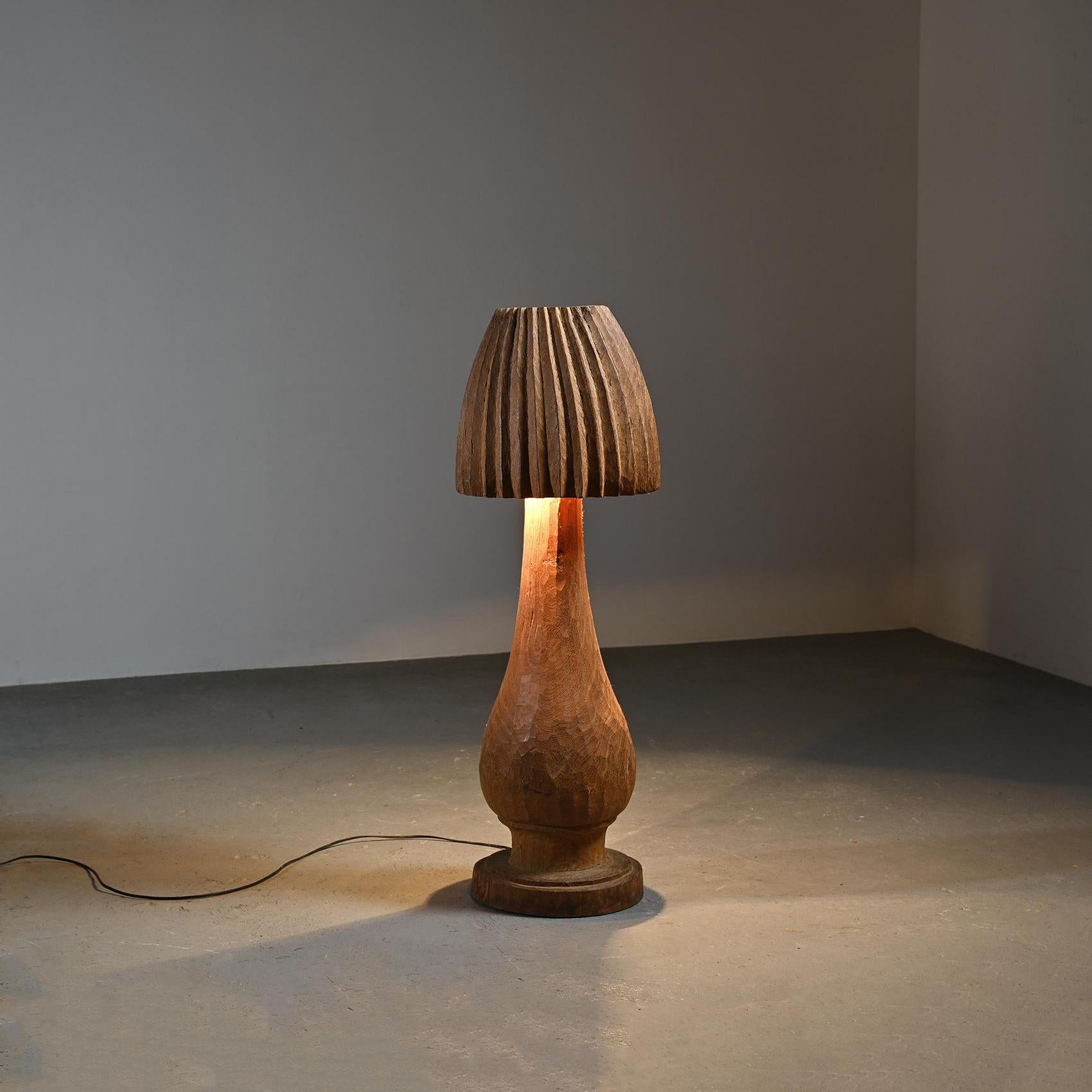 Grand lampadaire à deux lumières, en forme de champignon, réalisé en taille directe à la gouge. Cette pièce unique se distingue par sa facture brute et expressive, mettant en valeur la texture du bois sculpté. 

L'utilisation de la gouge pour