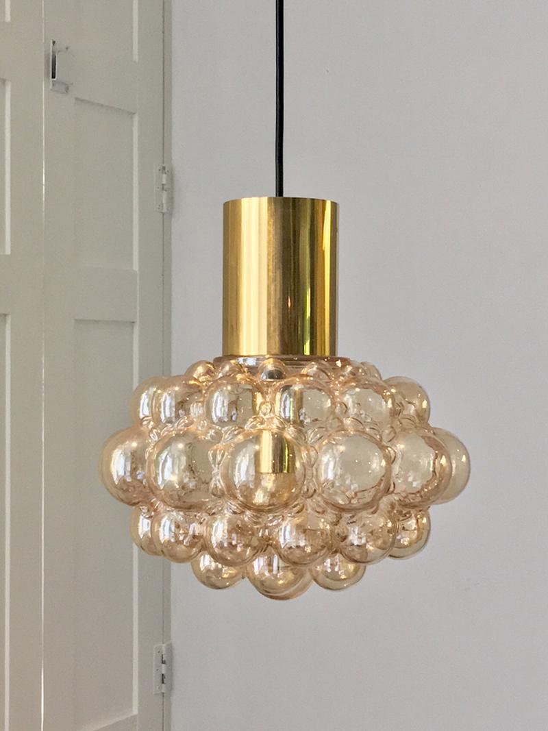 Bubble glass chandelier or pendant light by Finnish designer Helena Tynell - wife of designer Paavo Tynell - for Glashütte Limburg of Germany.  

This attractive fixture comprises a glass shade of pale amber, with brass tubes above and within the