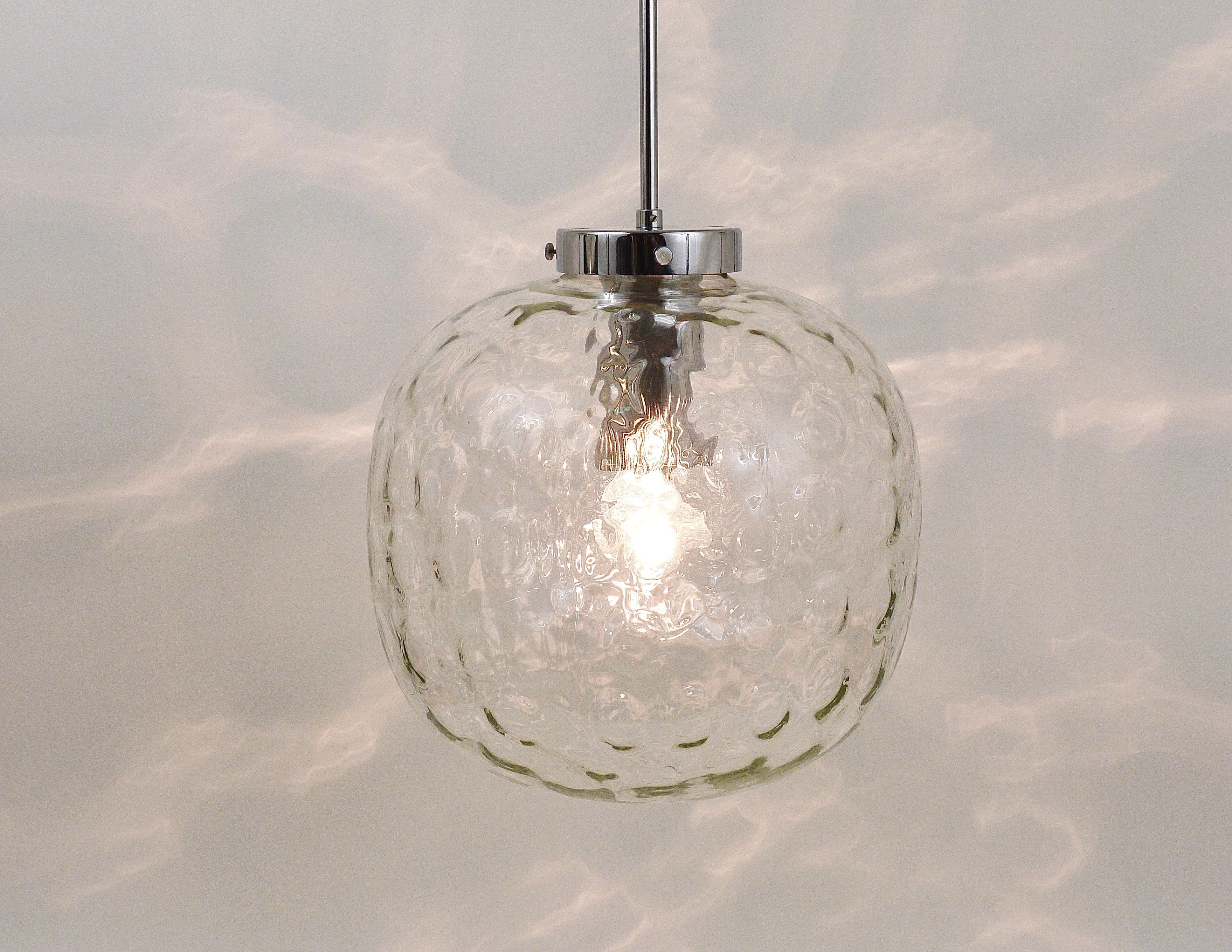 A beautiful Space Age pendant light with a large clear glass globe and chrome-plated hardware. The globe is hand blown and has lovely round melted dots in the glass, this lamp is giving a wonderful light. It has a diameter of 12 in. Executed in the