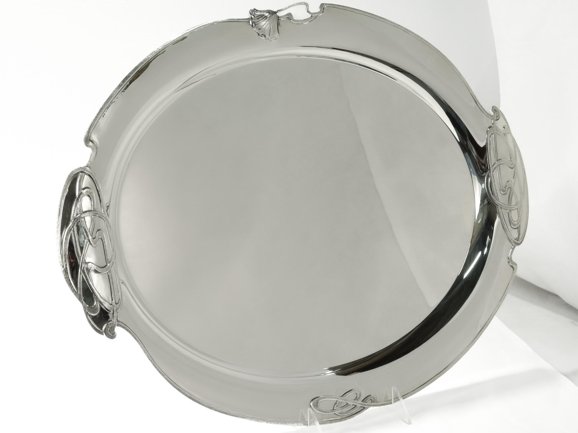 Un grand plateau de service de style Art Nouveau pour la table.

Par Buccellati.

En argent sterling.

Le bord est en forme, les poignées sont ornées d'éléments stylisés en fil tissé et le côté est orné d'une fleur de pavot figurative.

Entièrement