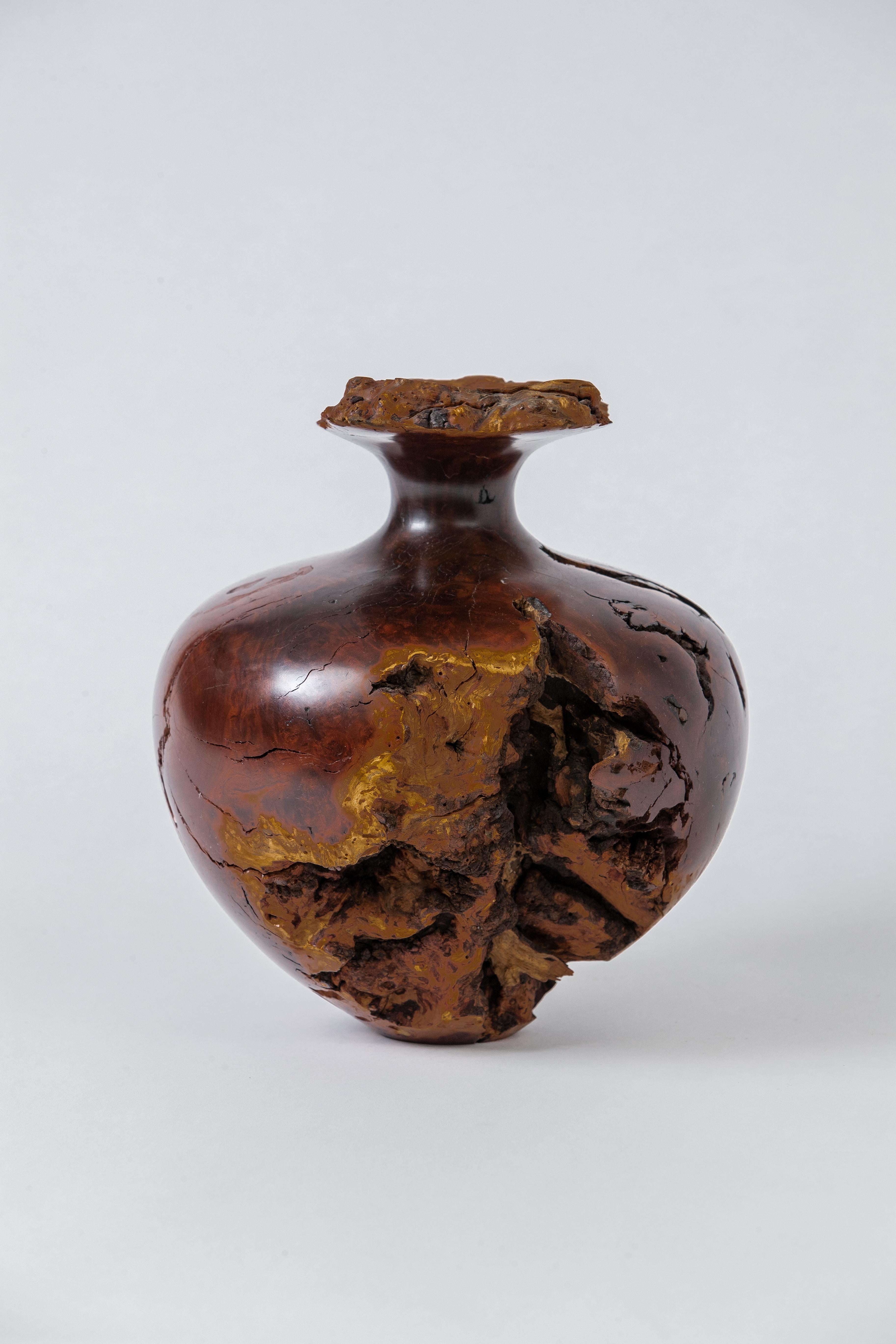 A large olive burl wood bud vase, carved out of a single block. The opening has a little glass tube for a single flower.