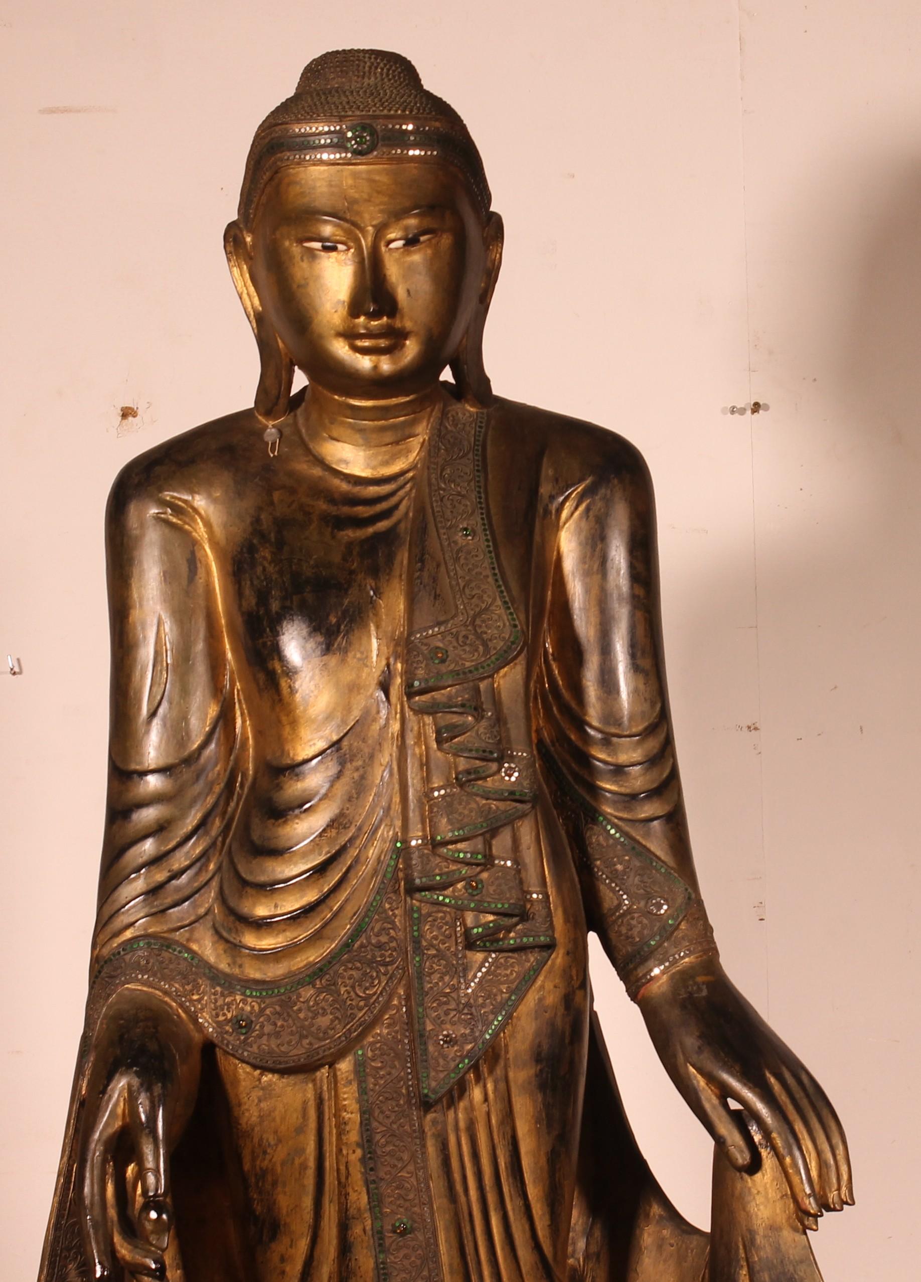 Superbo e importante Buddha del periodo Mandalay proveniente dalla Birmania del XIX secolo in legno dorato su una base di legno.

Grande e raro Buddha con una patina superba e riccamente decorato con perline di vetro. Nella mano destra tiene il