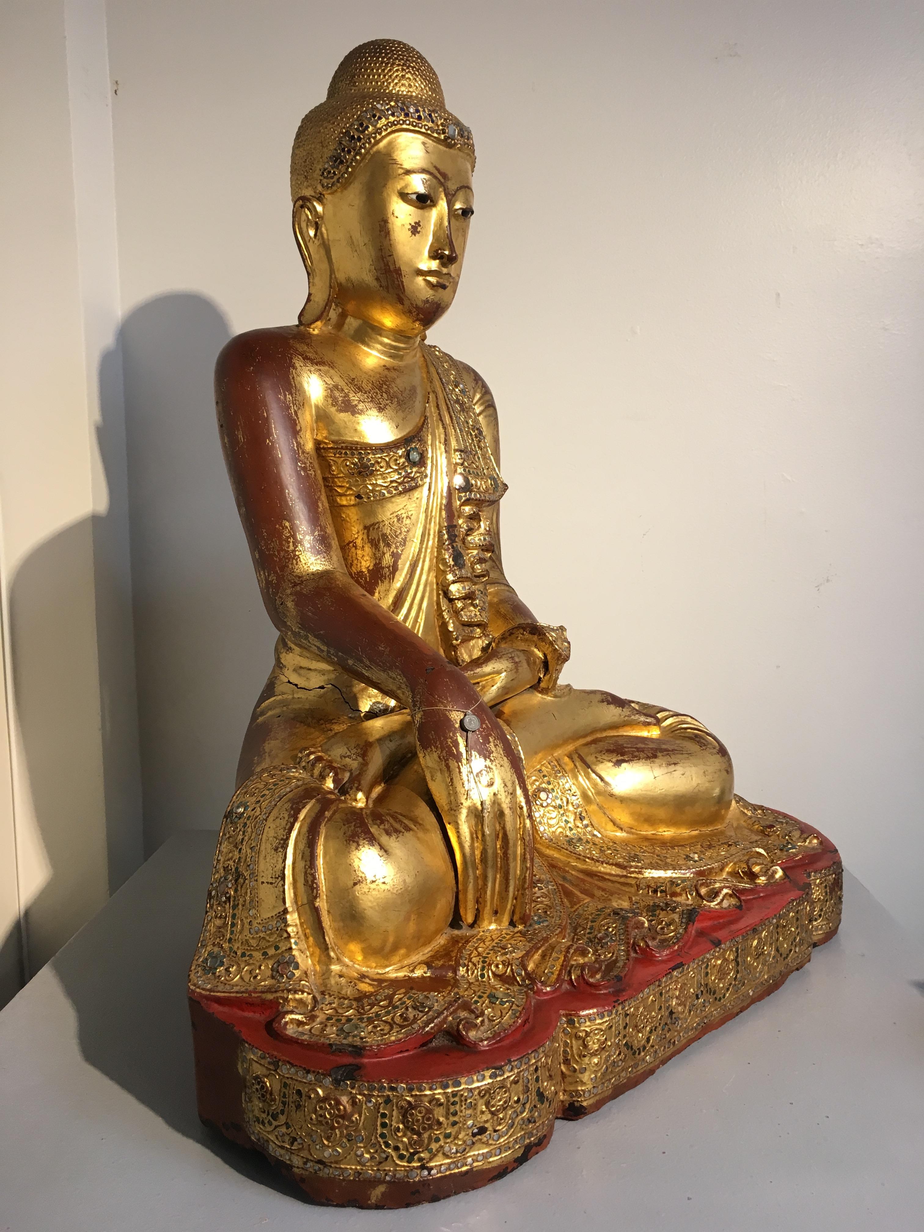 A wonderful classic Burmese Mandalay period carved teak image of the Buddha, circa 1900. The figure lacquered, gilt and embellished with glass 