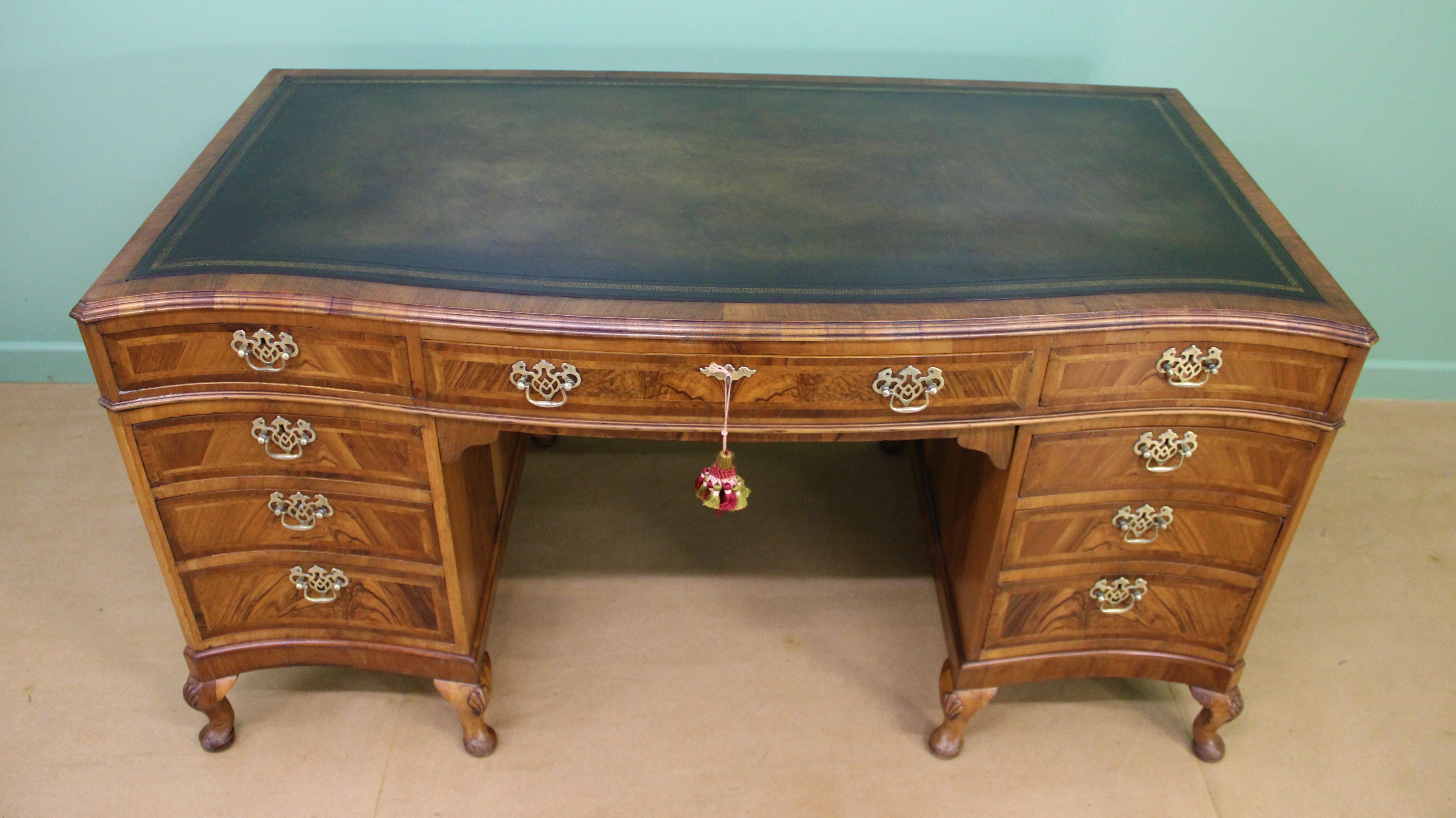 A very good Queen Anne style burr walnut pedestal desk of generous proportions. Well constructed in solid walnut with attractive burr walnut veneers. Of serpentine form with a series of 9 drawers, all fitted with their original solid brass handles.