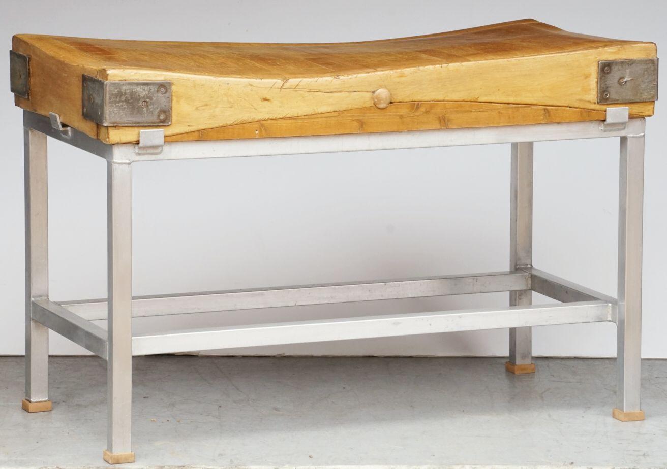 A fine large English butcher's chopping block or table, featuring a rectangular sloping block or slab of iron-bound wood set upon a sturdy bottom tier four-legged support stand or stretcher frame of metal, the feet with decorative wood accents.