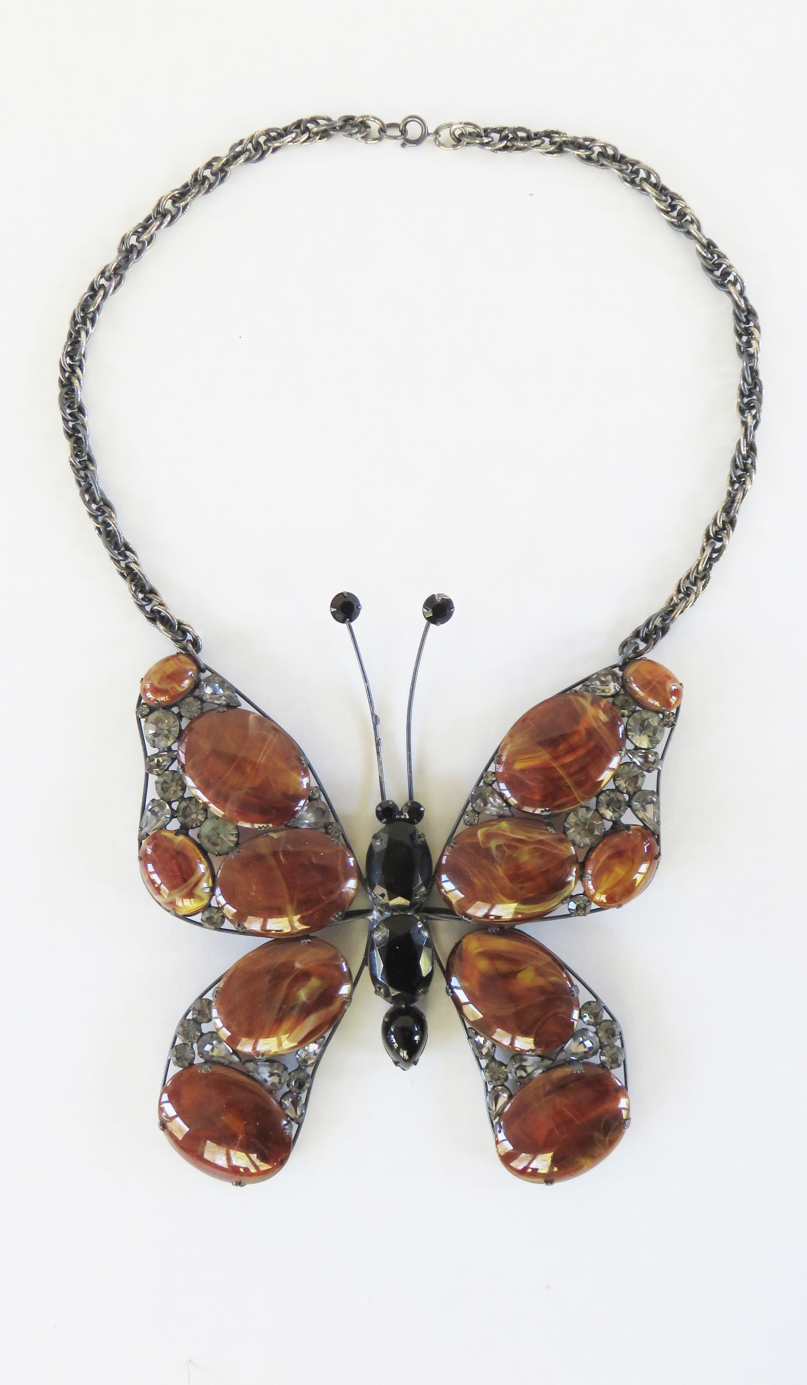 A fabulous large faux turtle shell and glass butterfly pendant necklace. It has a wing shaped metal frame onto which discs of different sizes of faux turtle shell and glass rhinestones are attached. The center body is comprised of 3 black glass