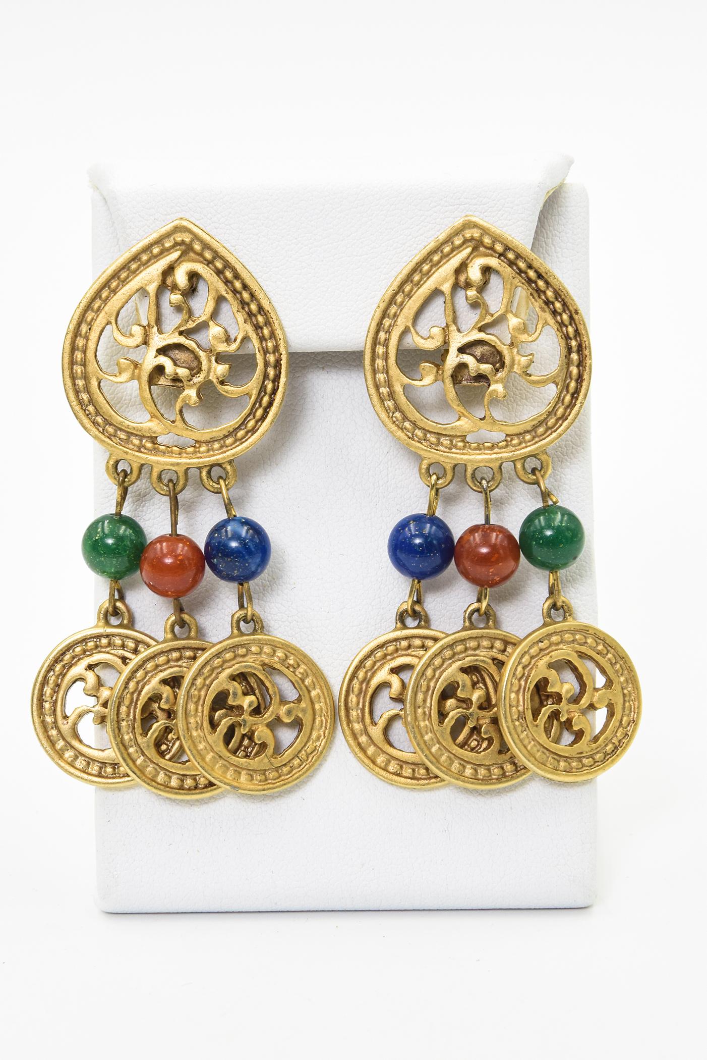 Dramatic gold toned drop earring with punched out teardrop design on the ear which is repeated with 3 similar  round dangles.  The dangles drop from a green, orange and blue glass bead.  They are clip-on so no piercing required.  They have no makers