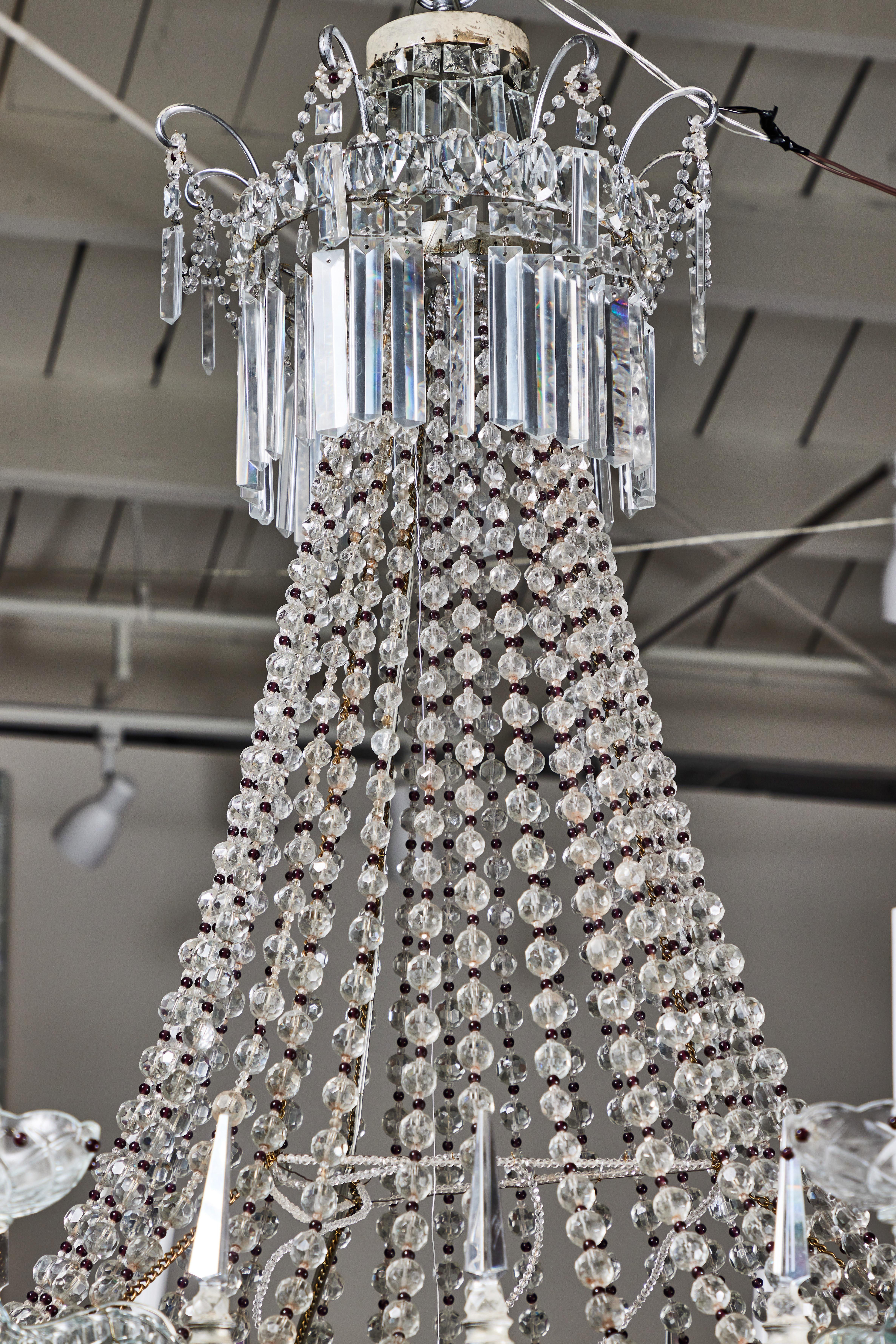 A grand, circa 1930, eight-arm, hand-beaded, Geneovese chandelier. Long swags of clear and ruby red crystals link the basket and top tiers, both embellished with beveled crystal drops.