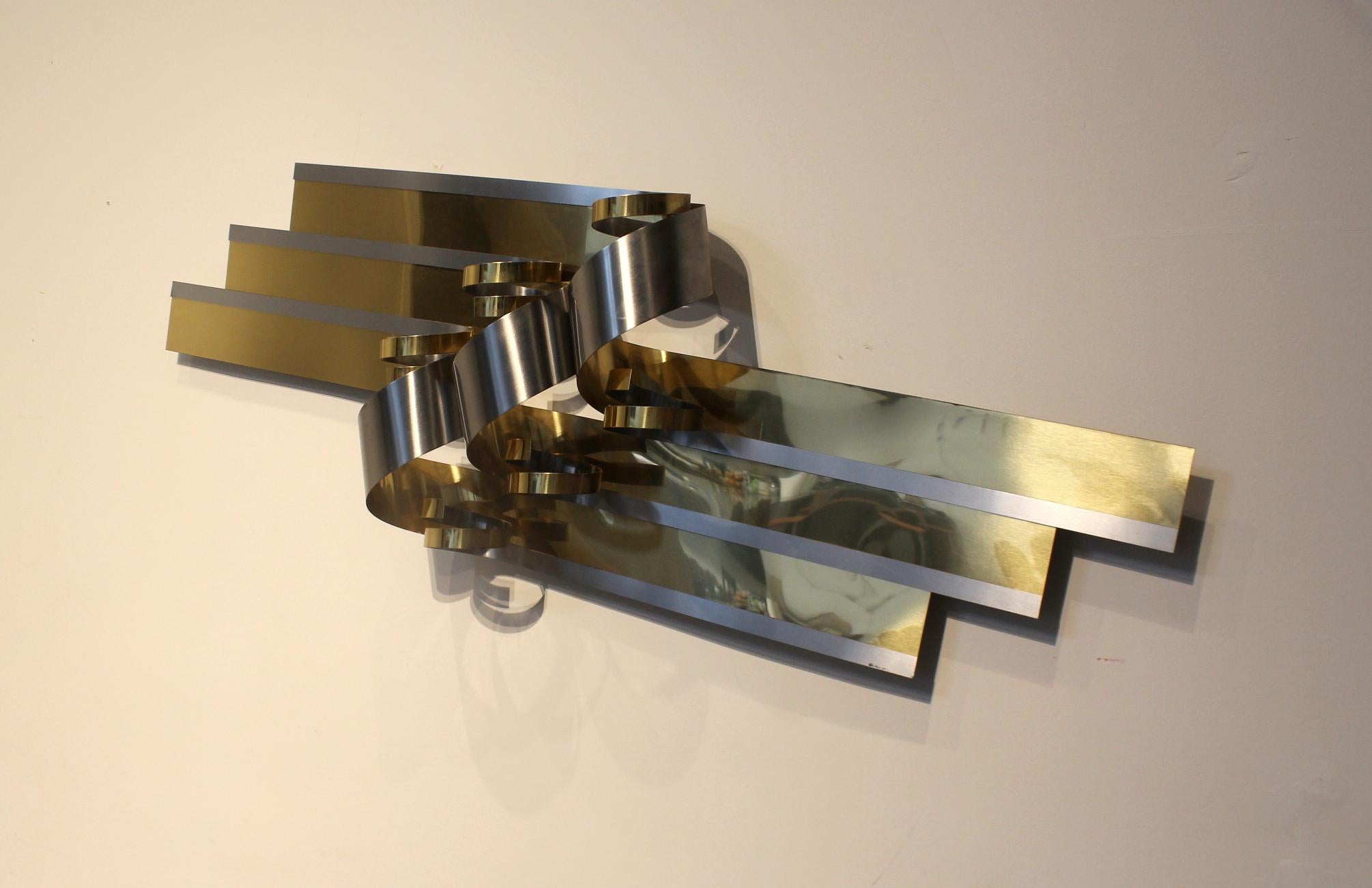 Beautiful chrome and brass ribbon wall sculpture by Curtis Jere. Signed and dated C. Jere 1989 on bottom right. Bright fresh patina with minor signs of wear.