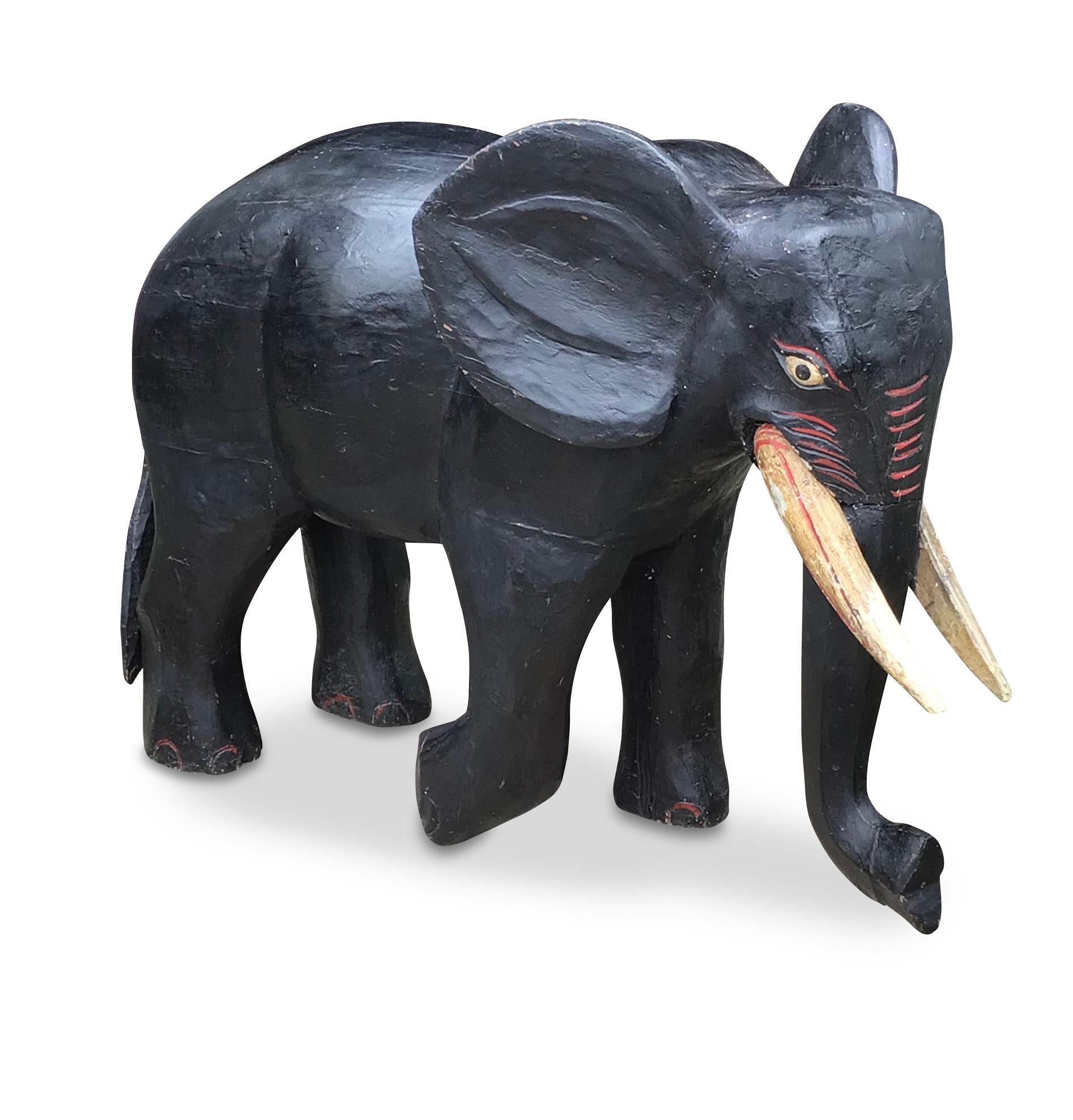 Early C20th unusual large carved wood sculpture of an elephant, with head turned slightly to right in a waking stance and one foot at rest, still retains its original decoration and charming paintwork to his face. A wonderfully fun and decorative
