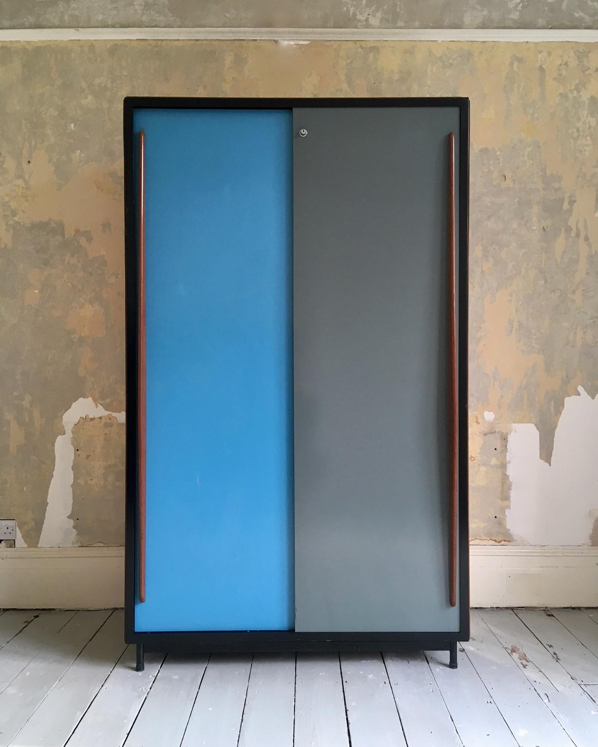 A large cabinet by Willy Van Der Meeren for Tubax, Belgium, 1950s.

The cabinet has a black metal frame and back, with blue and grey metal sliding doors with long, elegant fin-shaped wooden handles; the sides of the cabinet are plywood. The