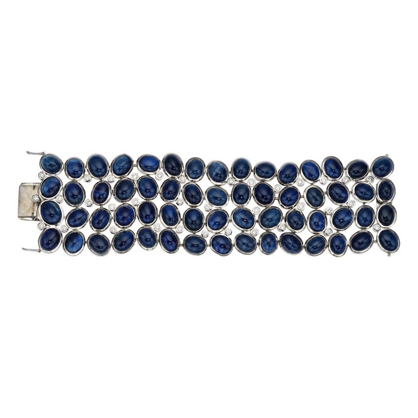 Four rows of cabochon deep blue sapphires go full circle around this indulgent bracelet with a seamless finish. The sapphires are bezel set in 18K white gold with 2.47 carats of round cut diamonds. The box clasp and two safety latches on either side
