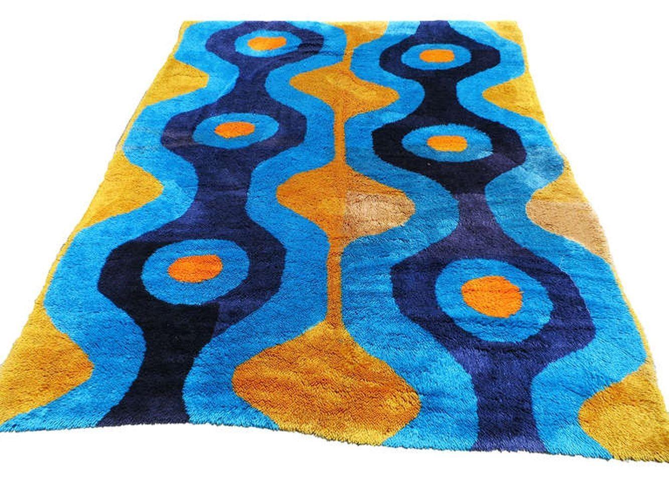Large California 7' hand-hooked wool area rug with an abstract picture of light blues undertones contrasting against dark blue hourglass shapes with a crisp yellow background. Great late Modernist rug that is sure to fit any decor.

California, 1970