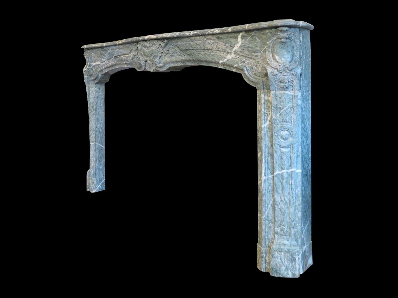 A large sophisticated and well carved fireplace in rare Campana green marble. The carved serpentine frieze with central cartouche of acanthus, C-scrolls and bell drops surround a plain medallion. Flanked by fielded panels on either side. The jambs