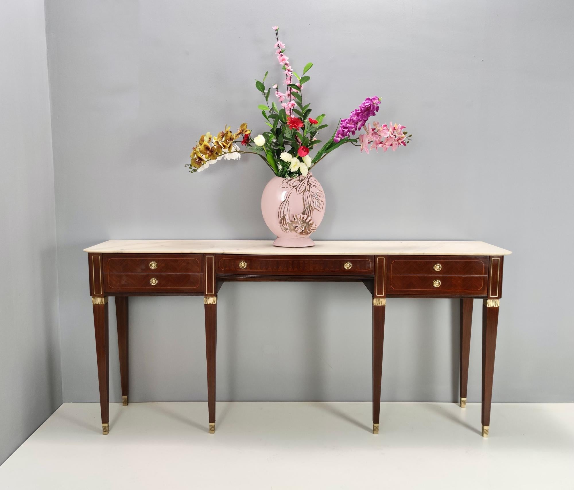 1950s.
This console table features a Canaletto walnut frame, a Portuguese pink marble top and cast bronze details.
Its drawers are made in maple with a layer of red velvet.
It is a vintage piece, therefore it might show slight traces of use, but it