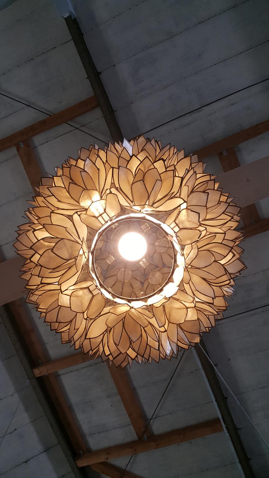 Large globular Capiz-shell lotus ball pendant light made in the 1960s. Each shell was handcrafted and assembled in a lotus flower pattern. The metal border is brass colored.
 