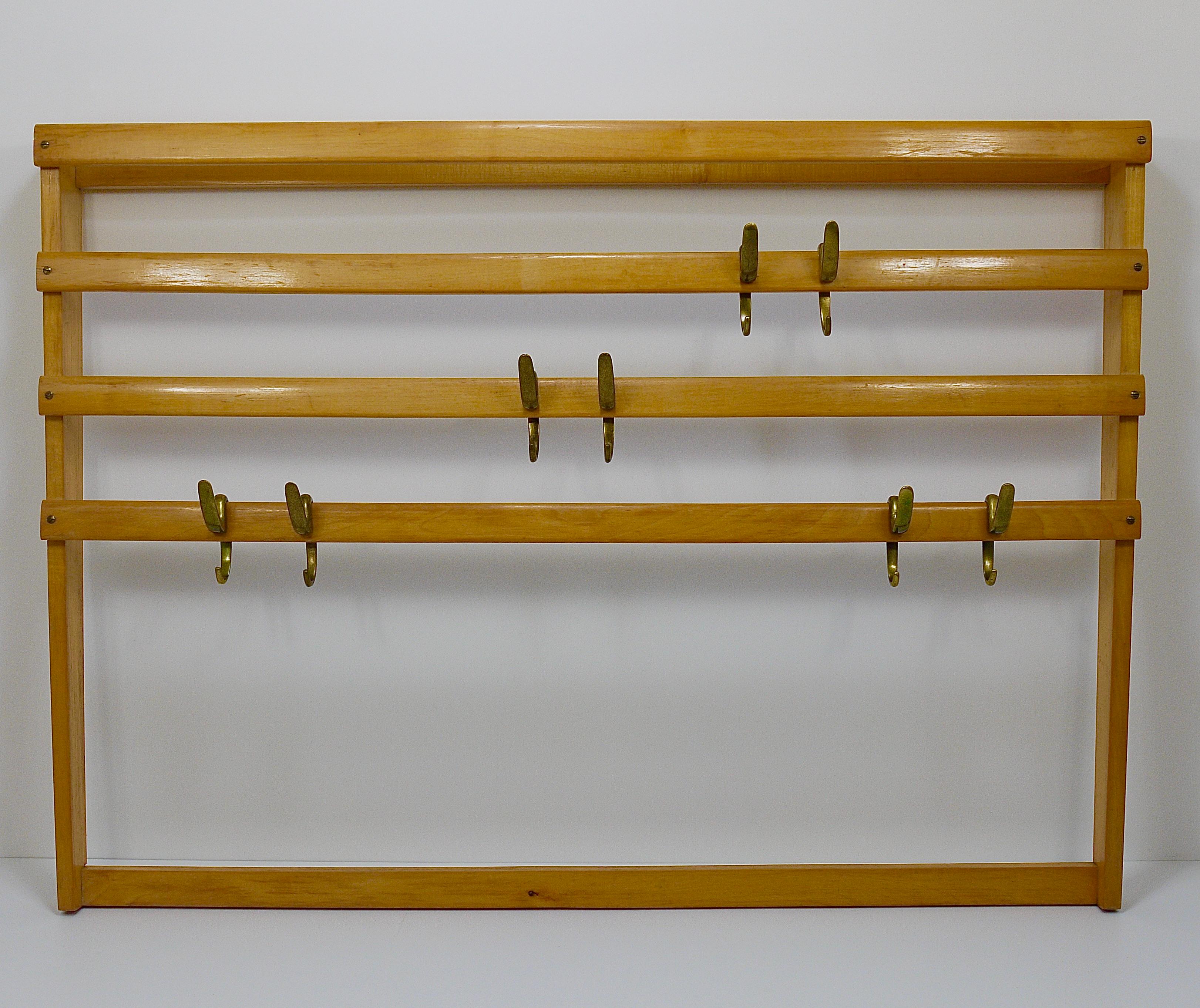 An elegant modernist wall-mounted coat rack from the 1950s. An original and old vintage object, designed and manufactured by the Austrian architect and designer Carl Auböck. The frame is made of beechwood with nice brass screws. It is equipped with