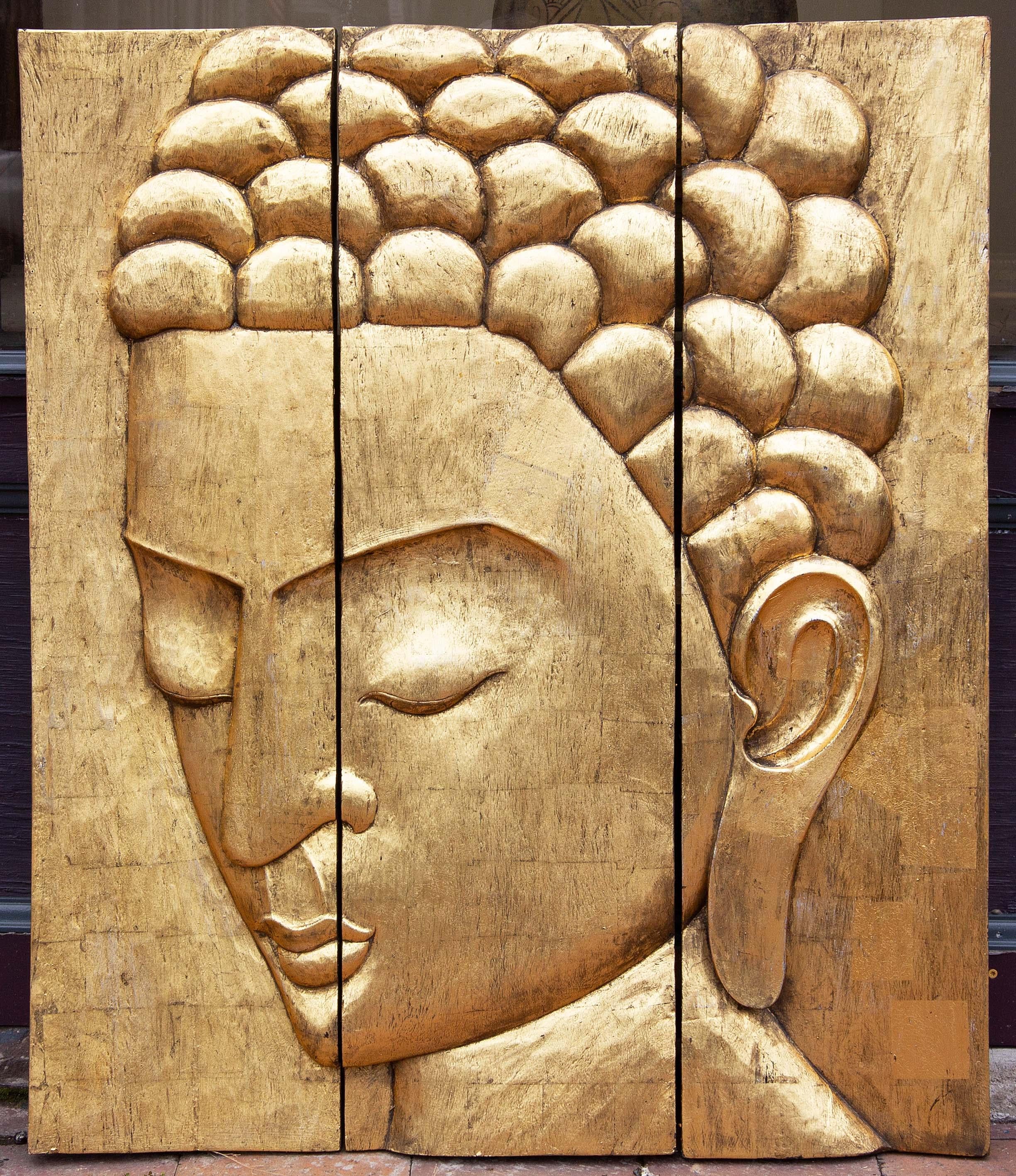 Profil d'un Bouddha sur trois panneaux de bois sculpté et doré. Milieu du XXe siècle.