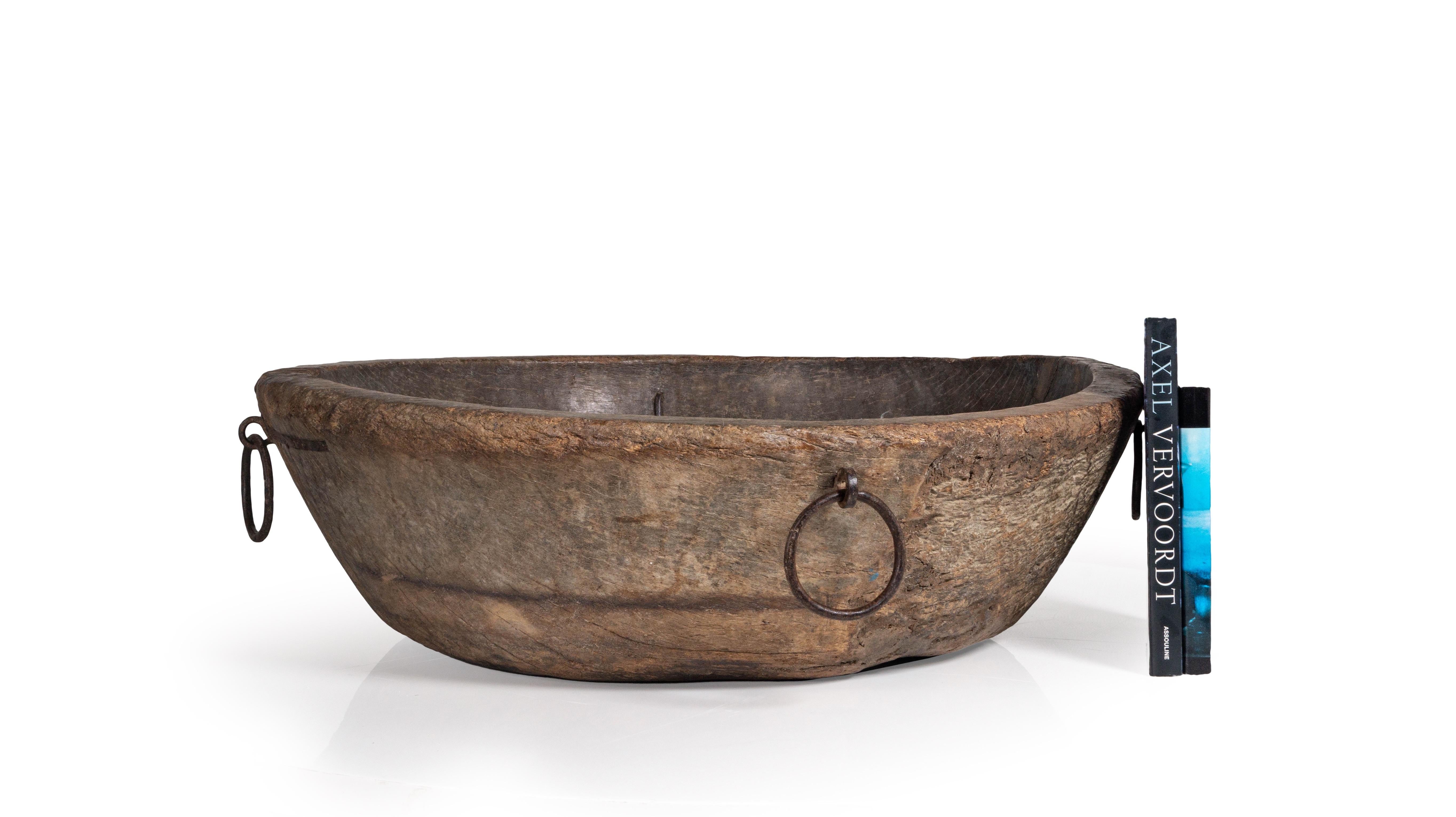 This large carved bowl with metal ring element handles is a part of our one of a kind collection, LeMonde, that is sourced from a small town in France. This beautiful bowl is carved from a single piece of wood adding to its uniqueness an its