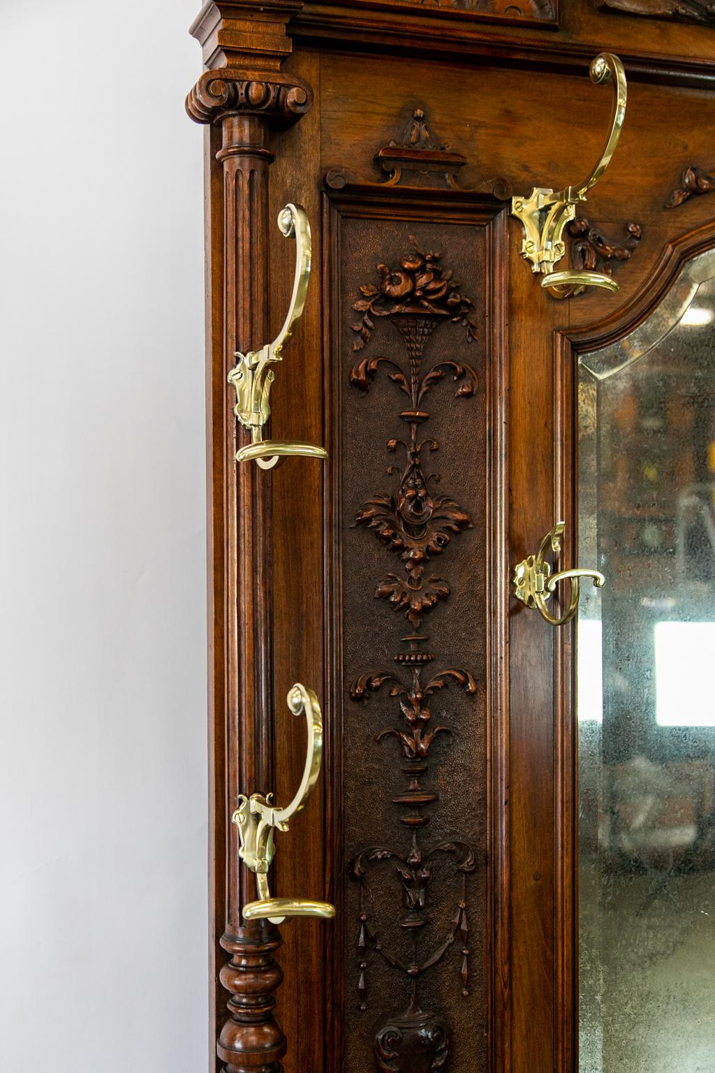 Large carved English solid walnut hall stand has all of the original hardware which is heavy cast brass and has been polished and lacquered for easy maintenance. The top half is profusely carved with intricate urns, arabesques, and baskets of grapes