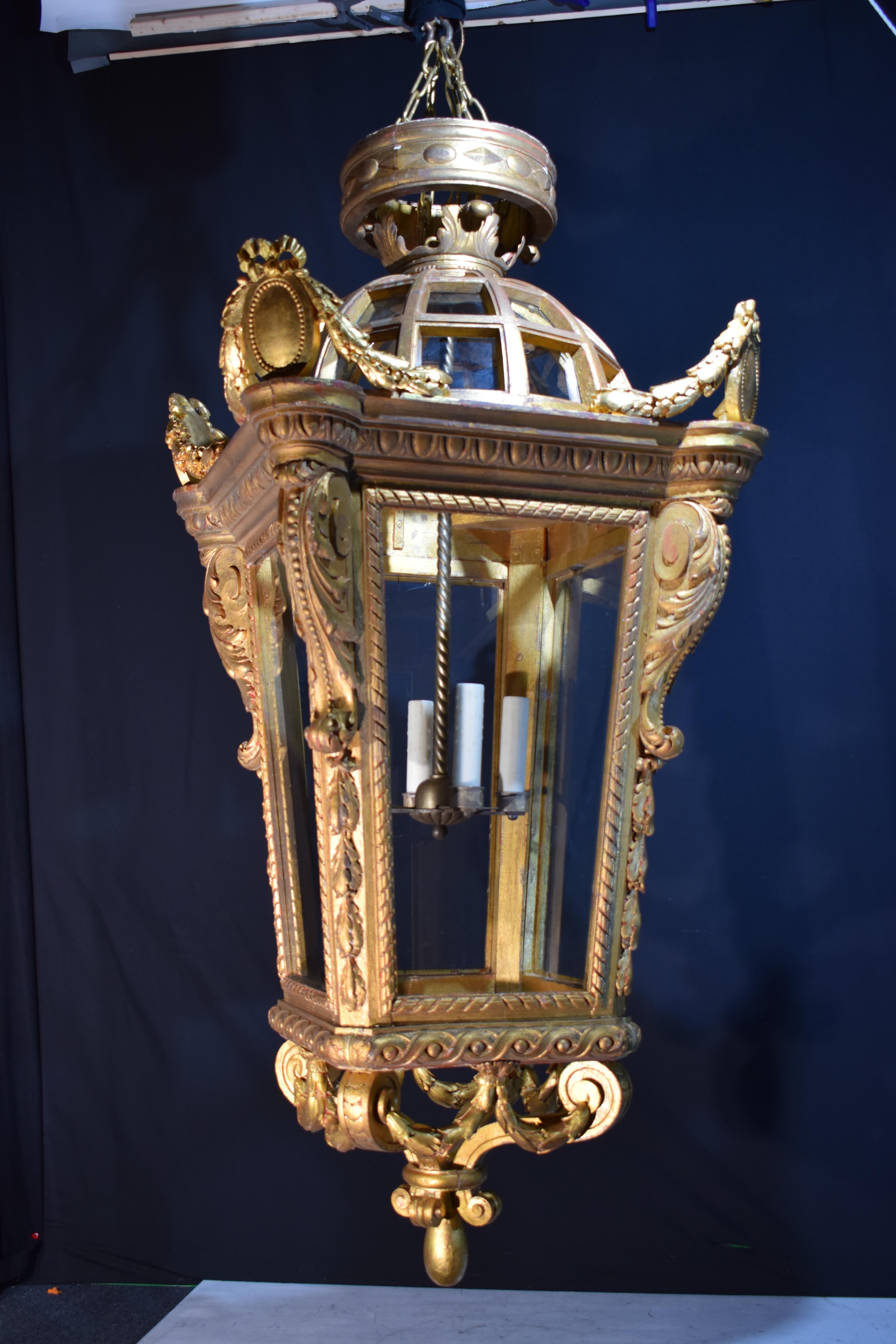 Très belle lanterne carrée en bois doré avec un dôme central et quatre boucliers flanqués de guirlandes. Panneaux de verre. Retiré de Whitemarsh Hall. France, vers 1910. 4 lumières. 
Dimensions : Hauteur 73