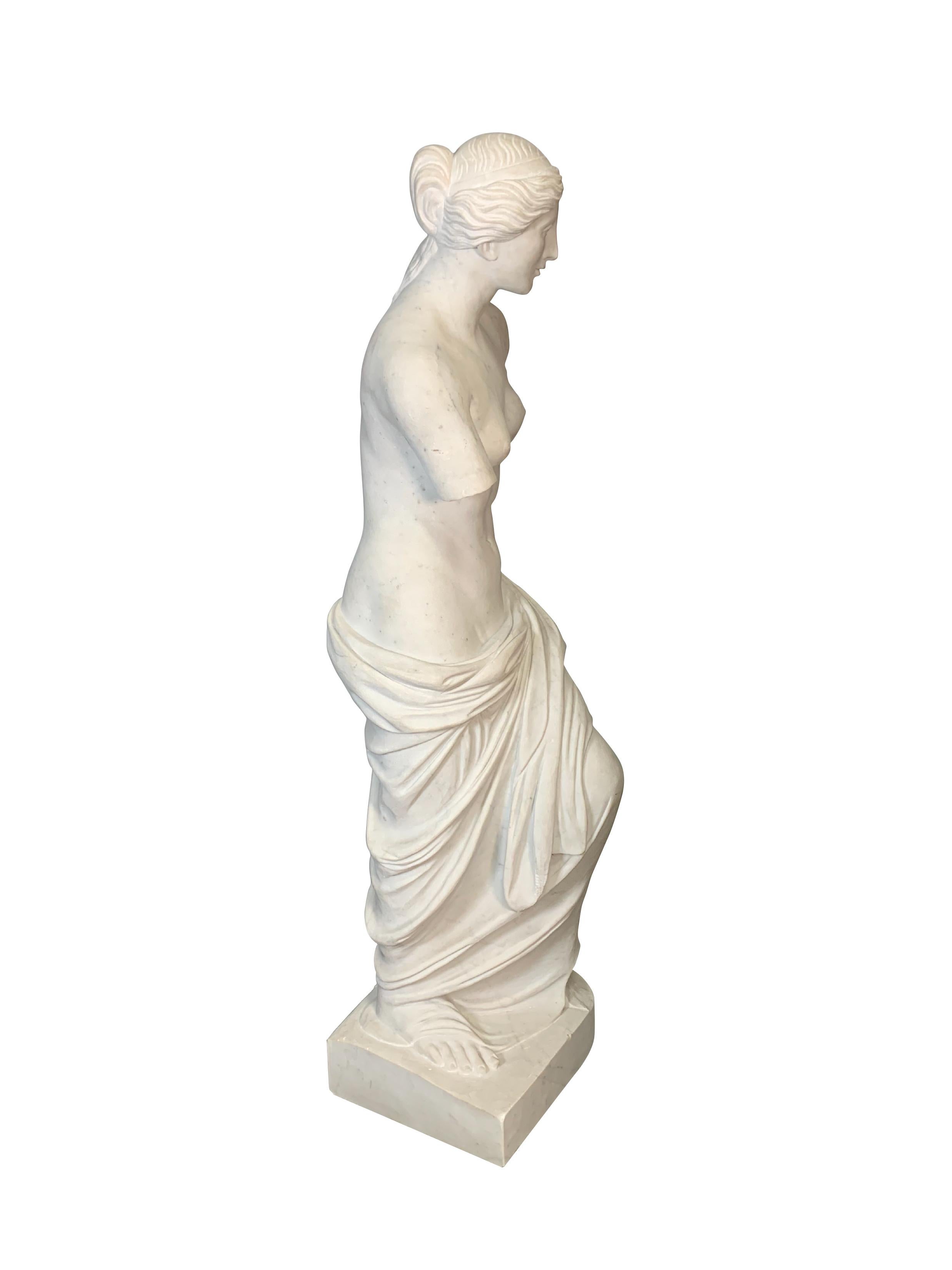 Cette élégante figure italienne en marbre sculptée à la main a été réalisée au début du XXe siècle. Elle est une copie de la célèbre sculpture en marbre Vénus de Milo (Aphoride de Milo en grec), déesse de l'amour et de la beauté. La statue originale