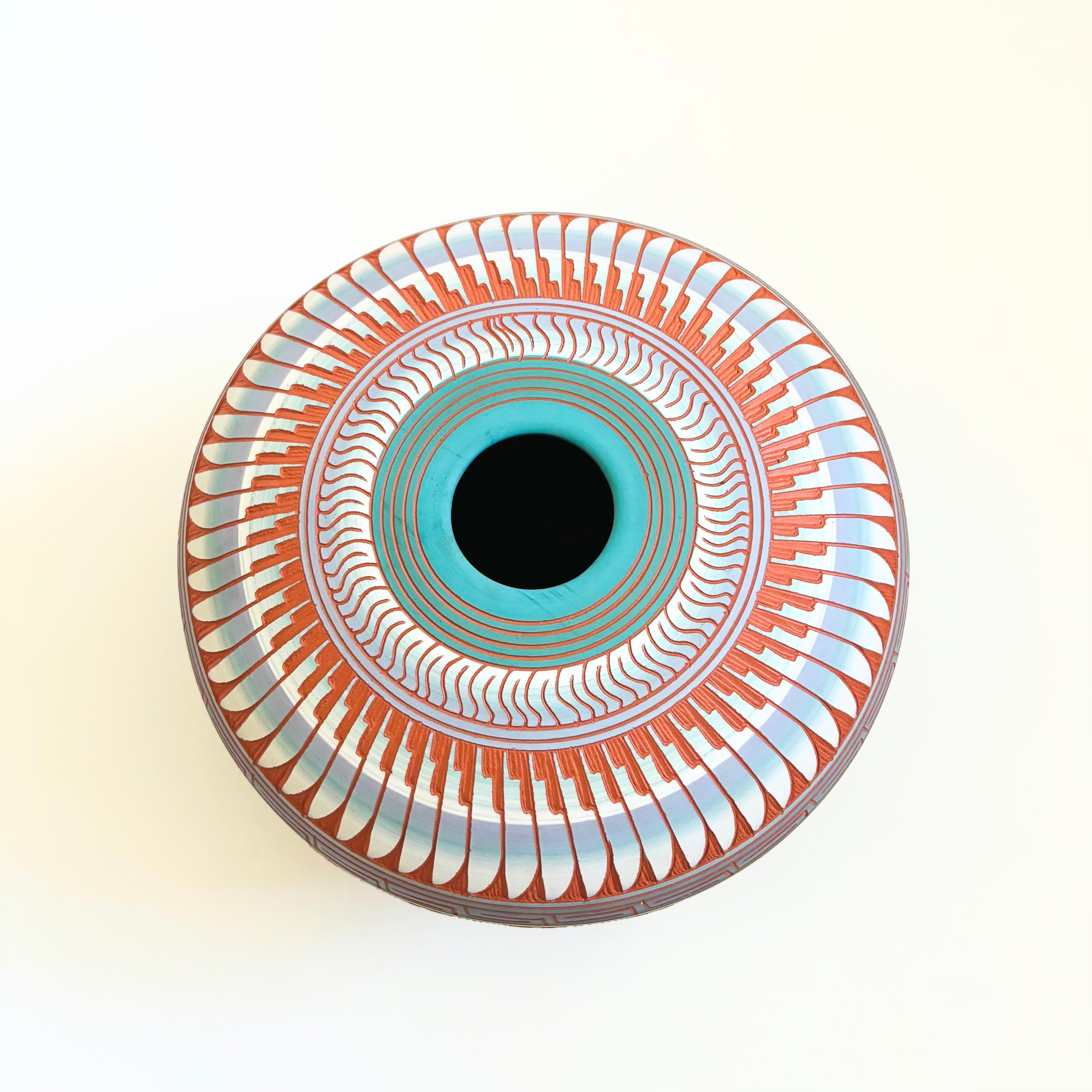 A beautiful vintage hand carved Navajo pottery vase. Bands of color wrap around the sides with a highly detailed pattern that has been hand carved into the sides of the vase exposing the natural terra cotta color of the clay below. Nice large size
