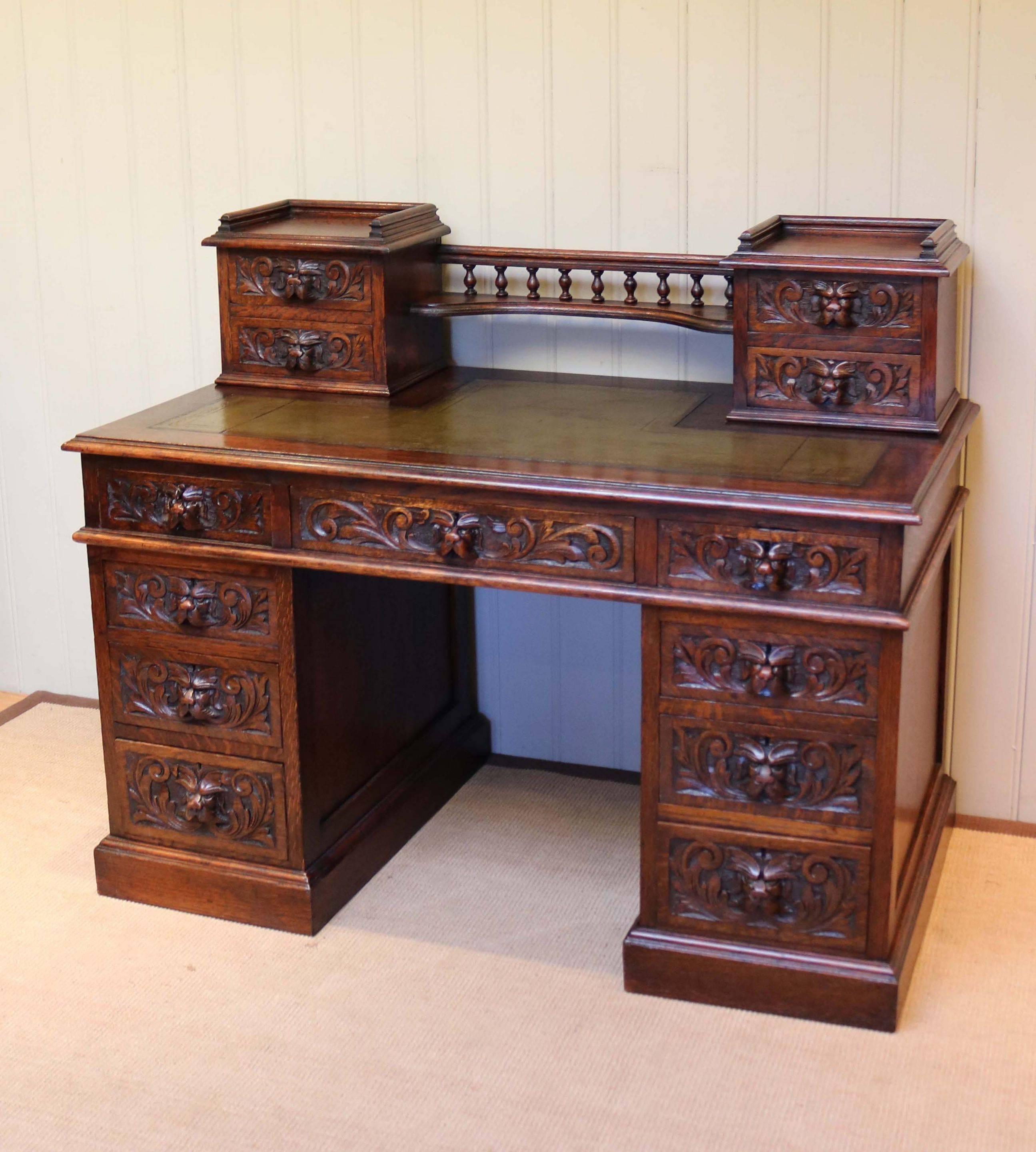 Large solid oak green man desk having a carved central drawer flanked by a further four to each side with a green leather top having an upper section with two drawers to either side united by a gallery. The height to the kneehole is 57cm.
 