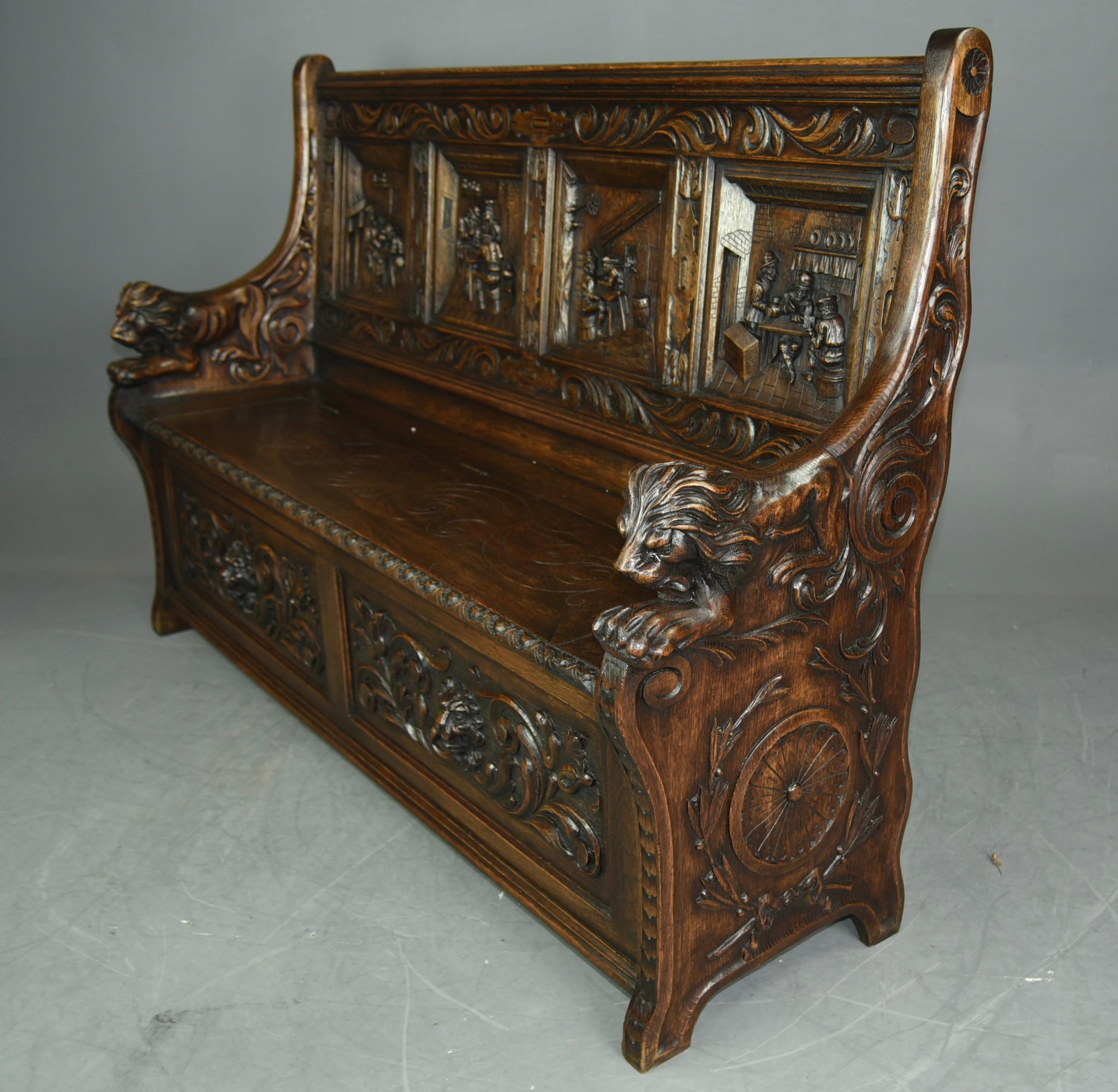 Fine Quality large four panel carved oak settle.
The settle has four magnificent carved panels to the back depicting tavern scenes all hand carved in solid oak. The arms ends with fine carved lions with great detail.
The settle has a lift up seat