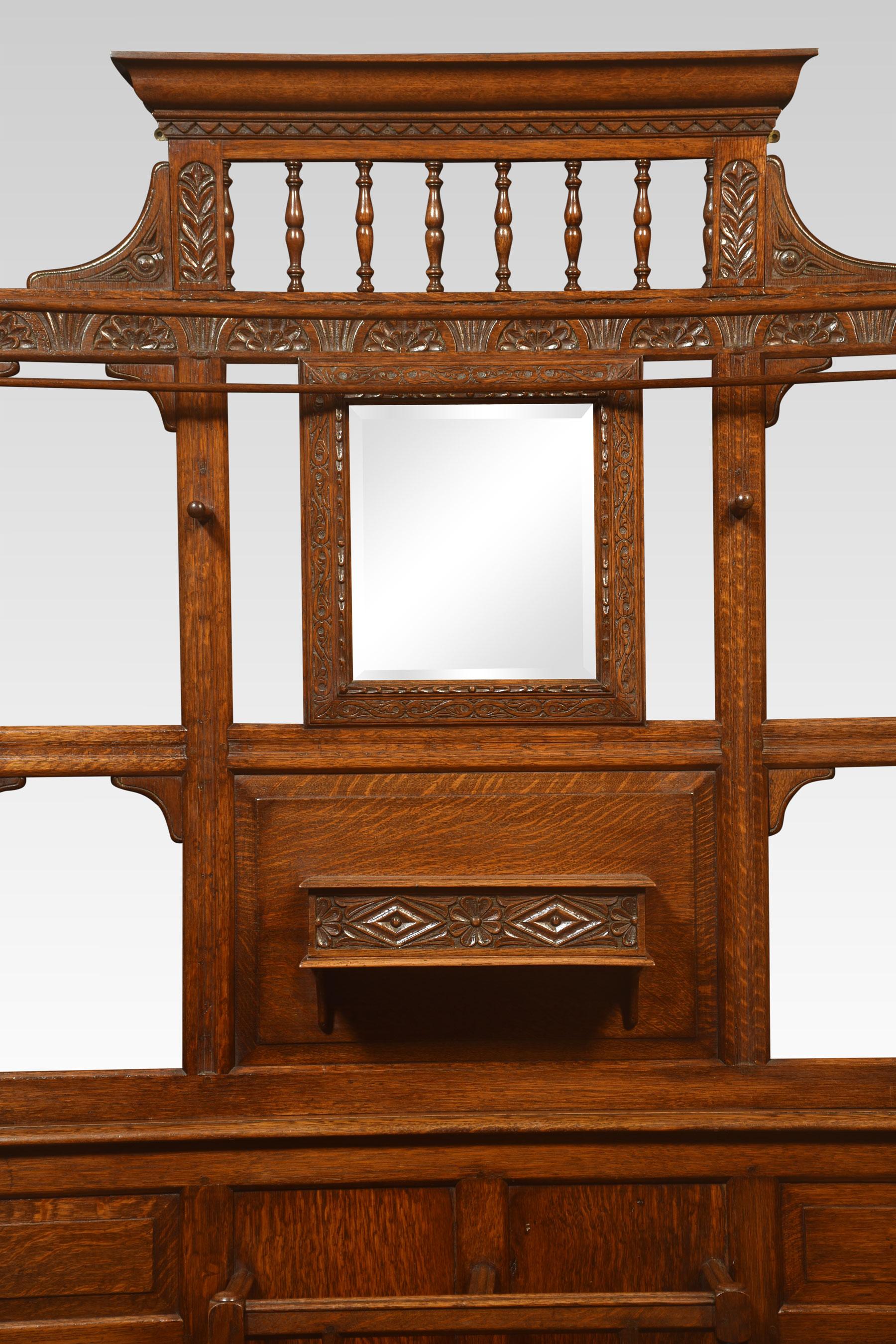 Oak hallstand, the superstructure with a central square beveled mirror surrounded by turned hooks and glove box. The base section having an umbrella stand and carved scrolling panel. All raised up on a plinth base.
Dimensions
Height 82
