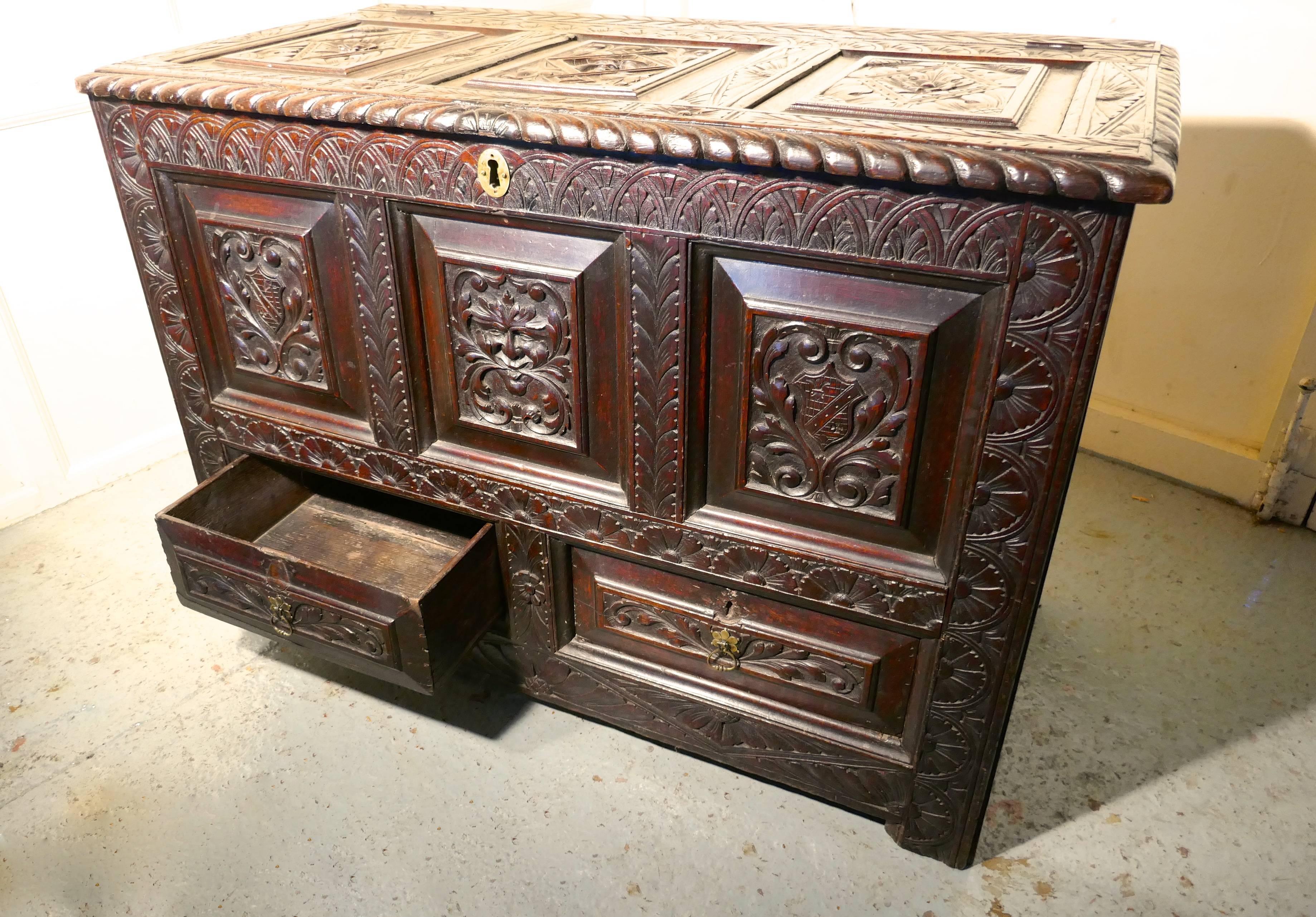 Large carved oak mule chest, green man marriage chest

This is a profusely carved marriage chest, the coffer has many detailed carved panels. On the front we have two family crests on either side of the green man’s face, and on the top we have